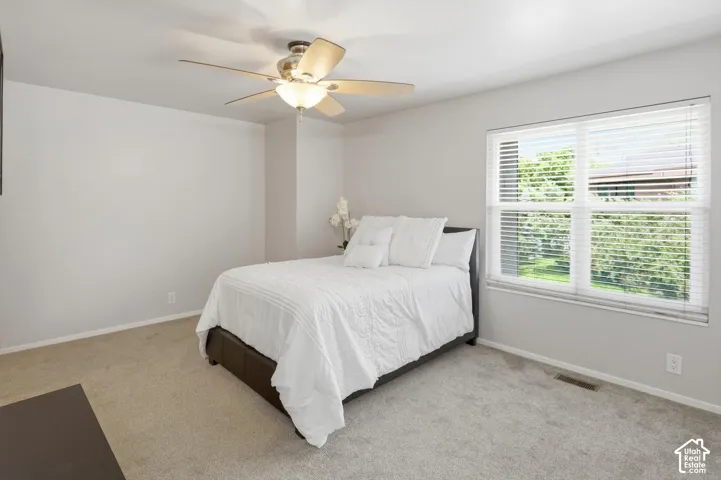 Carpeted room featuring a ceiling fan with integrated lighting, a window with horizontal blinds, and light-toned wall finishes