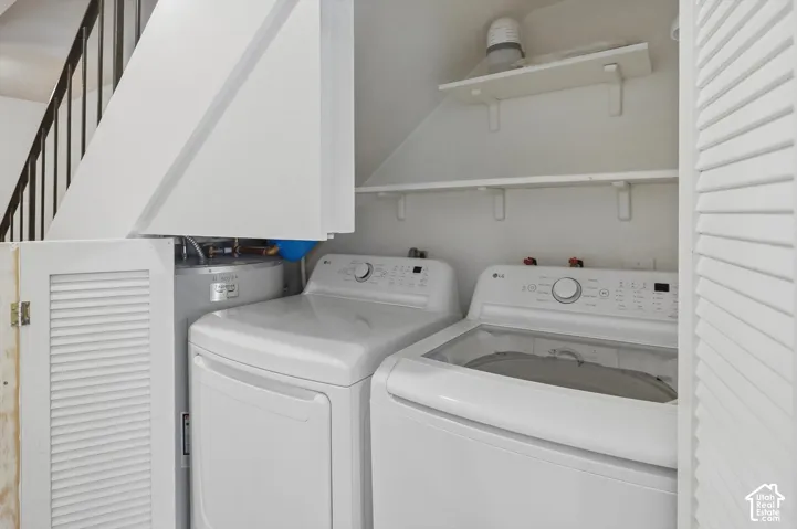 Dedicated laundry area featuring a white washing machine, white dryer, and built-in shelving