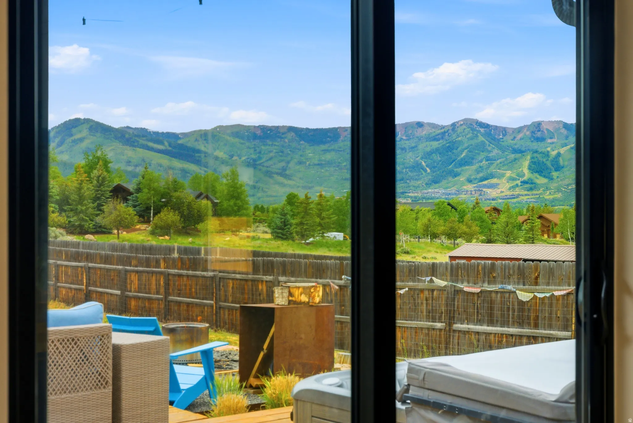 Sliding glass doors opening to an outdoor patio with a hot tub and mountain scenery
