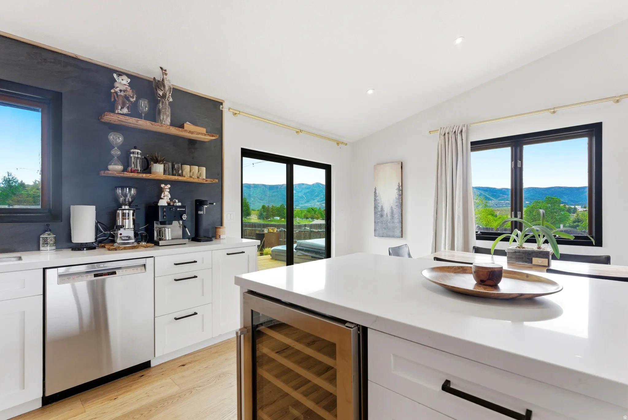 Contemporary kitchen featuring white cabinetry, a large center island with a built-in wine cooler, stainless steel appliances, and wood-finish flooring