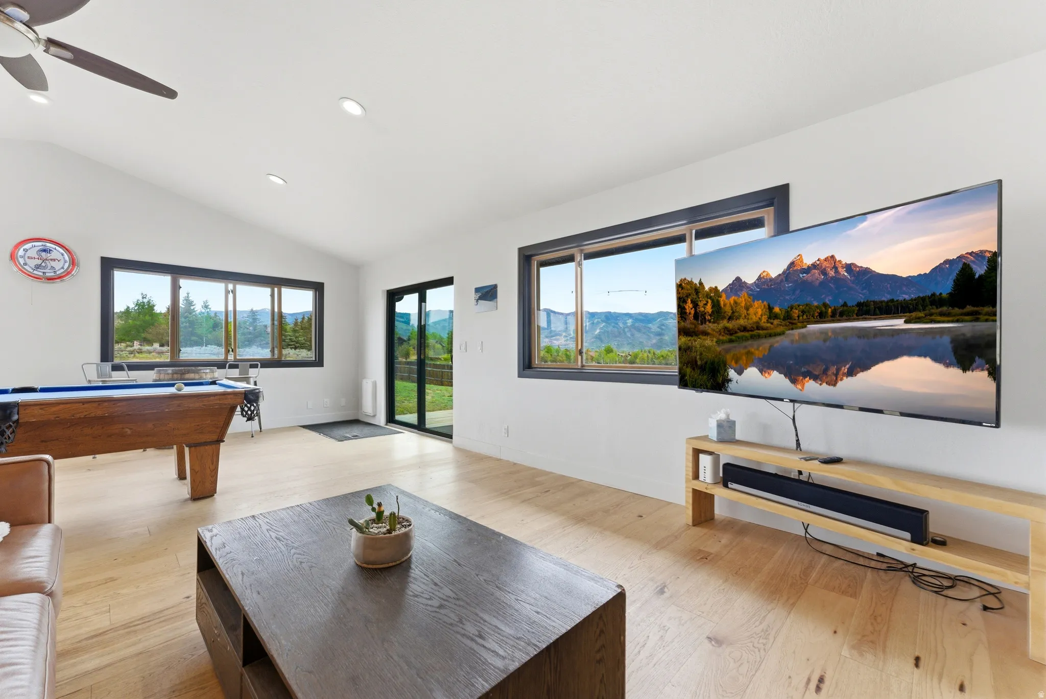 Bright interior space featuring vaulted ceilings, recessed lighting, wood-finish flooring, and expansive windows