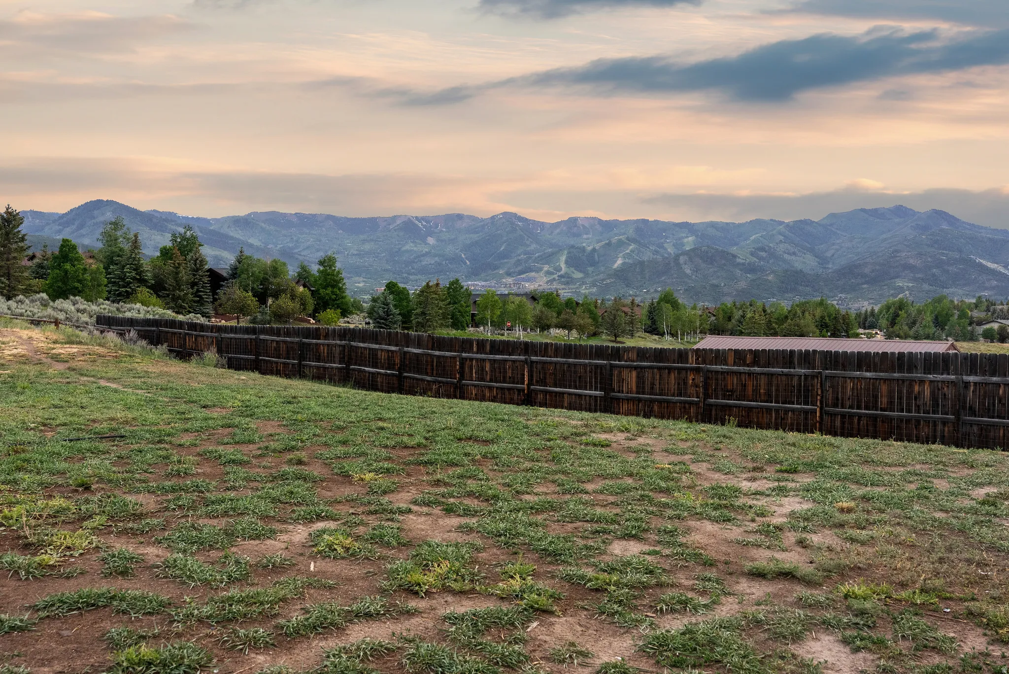 Expansive outdoor space featuring a dark wood privacy fence and distant mountain peaks