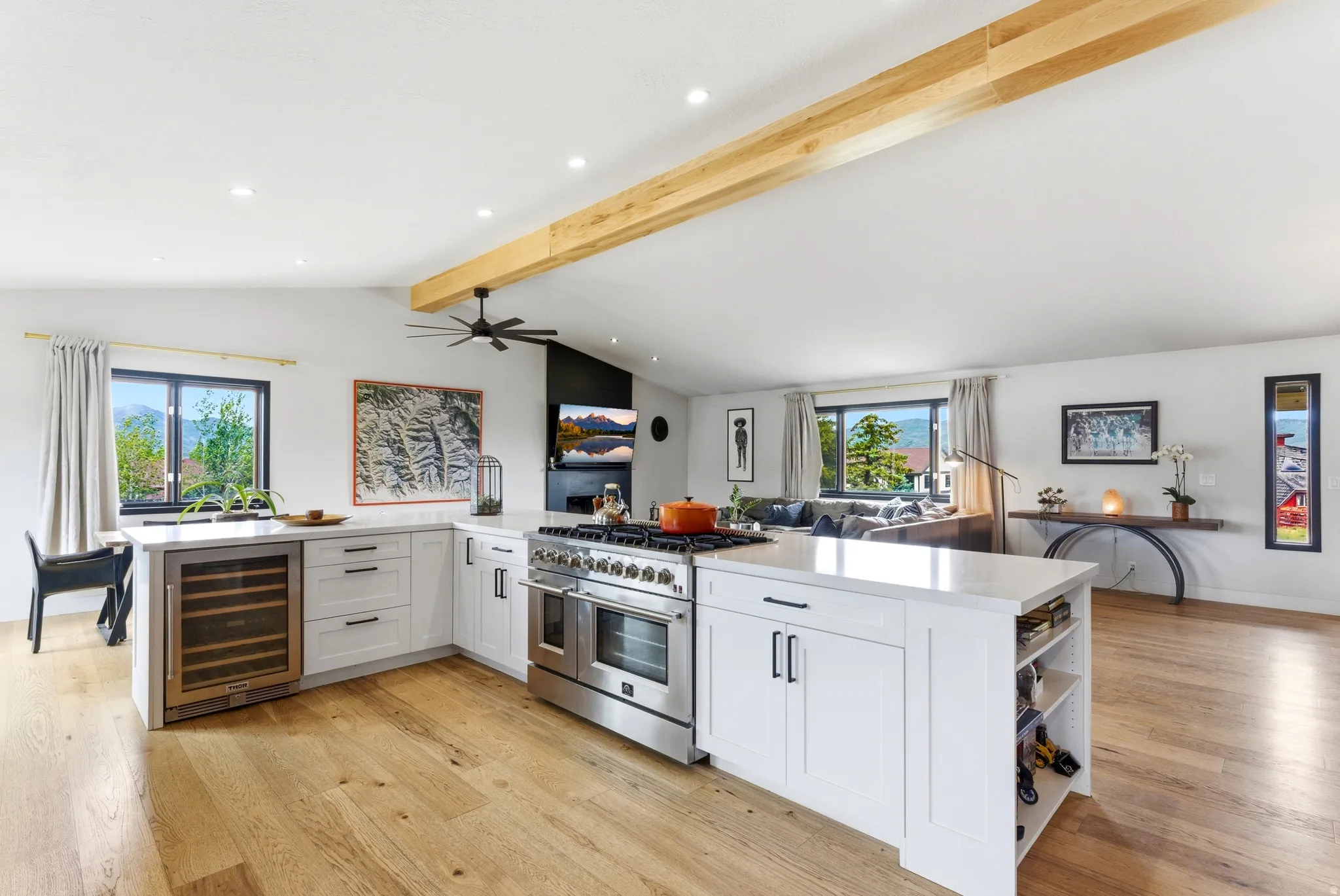 Open-concept kitchen featuring white cabinetry, quartz countertops, a built-in wine refrigerator, stainless steel range with double ovens, and wood-finish flooring