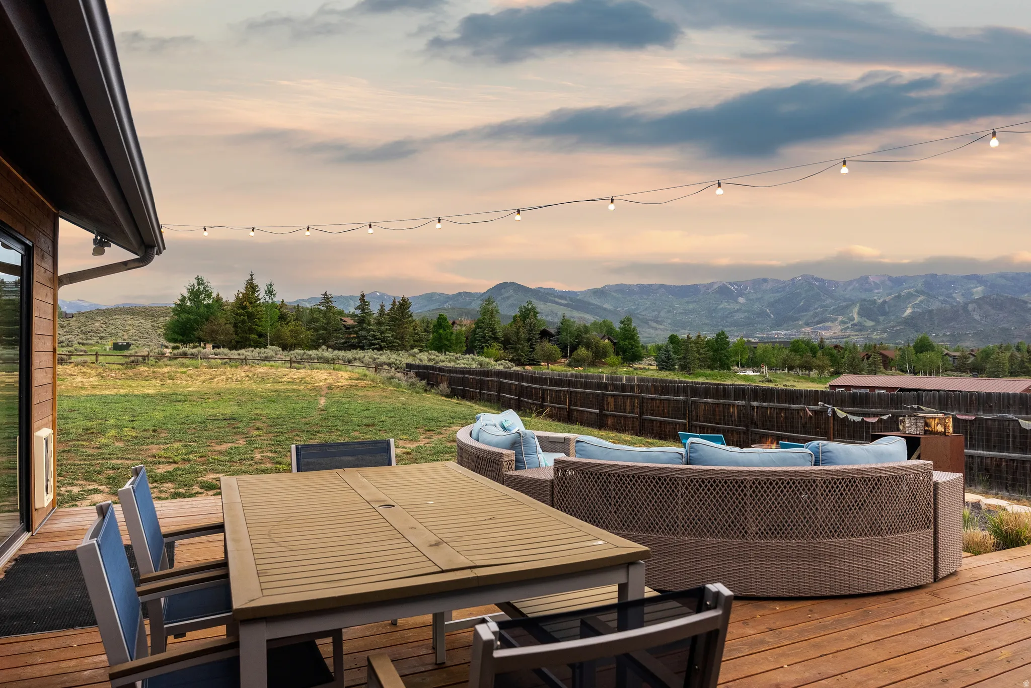 Expansive outdoor deck featuring wood-finish flooring, string lighting, and a mountain backdrop