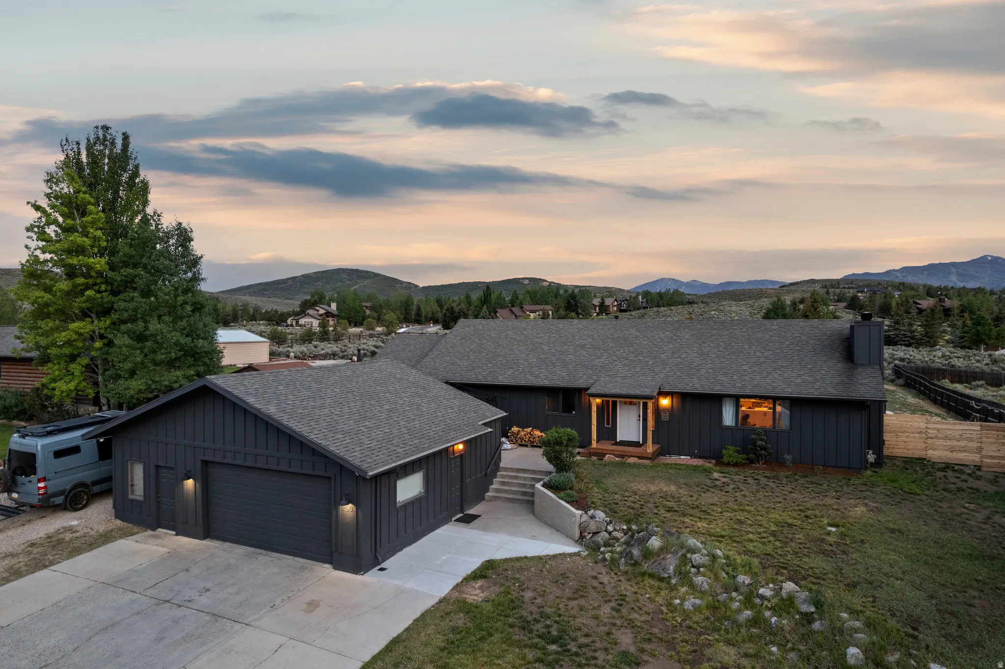 Modern exterior with dark vertical board siding, a two-car garage, and a concrete driveway