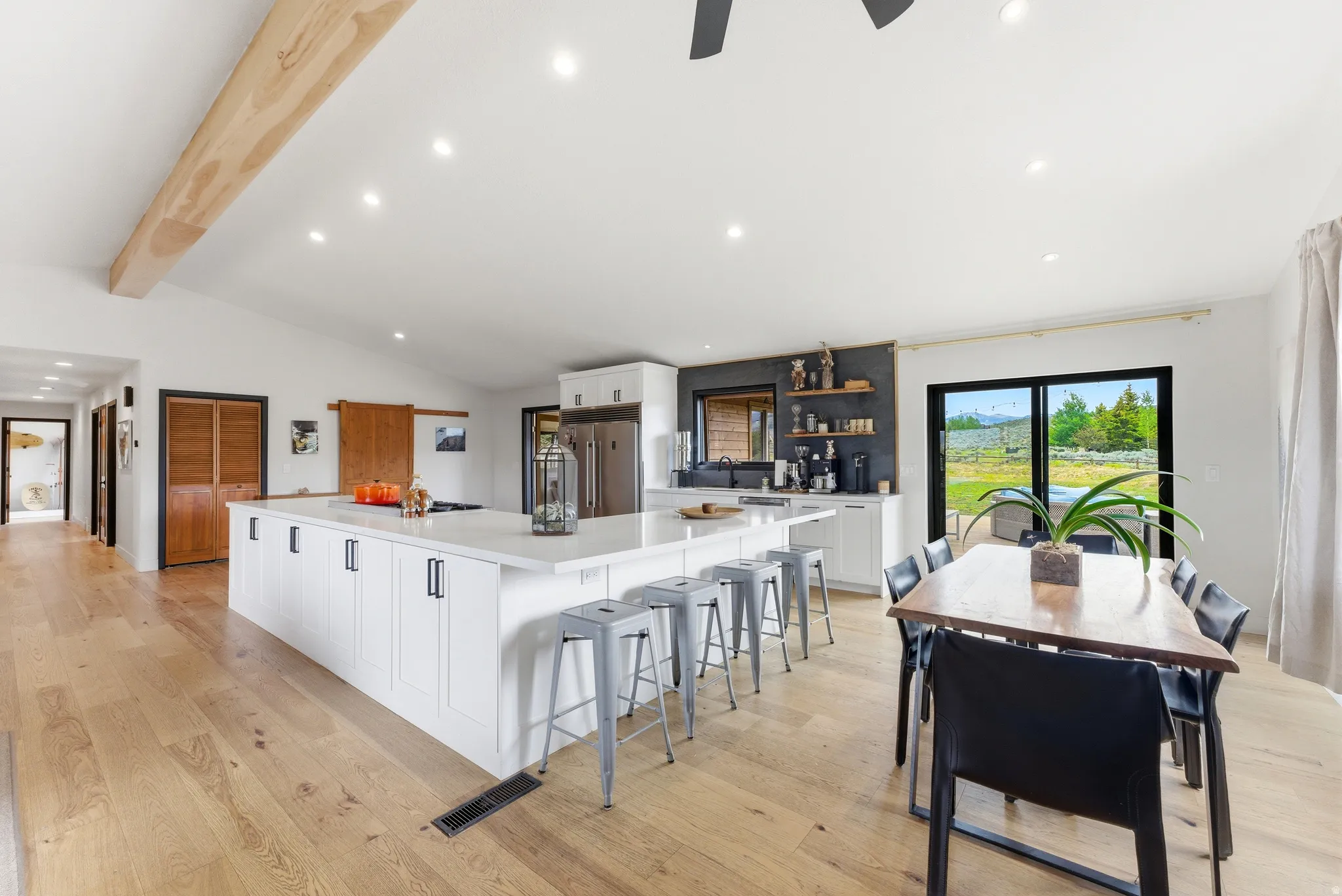 Spacious kitchen with a large central island, recessed lighting, wood-finish flooring, and a sliding glass door