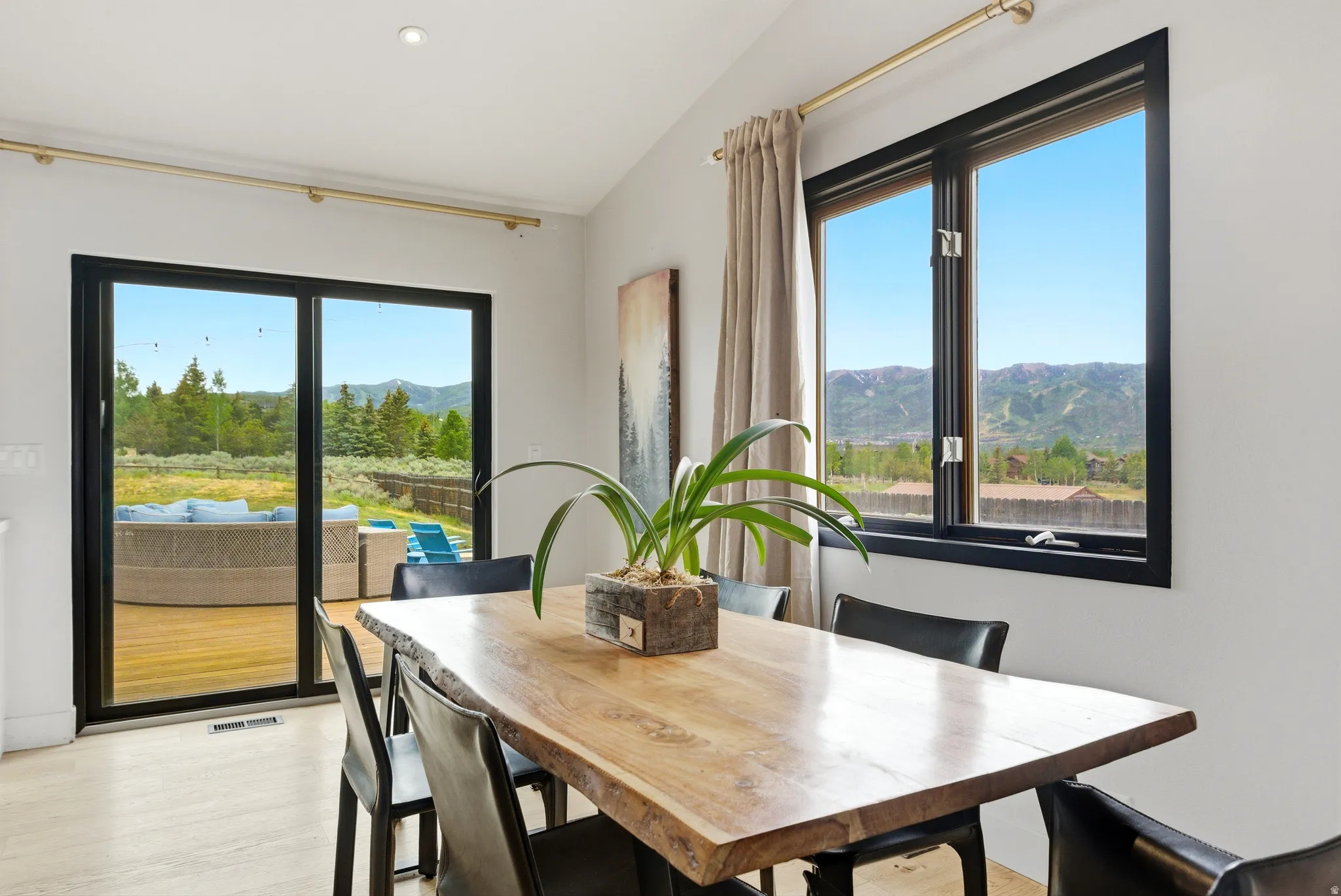Dining area featuring a live-edge wood table, black leather chairs, and recessed lighting