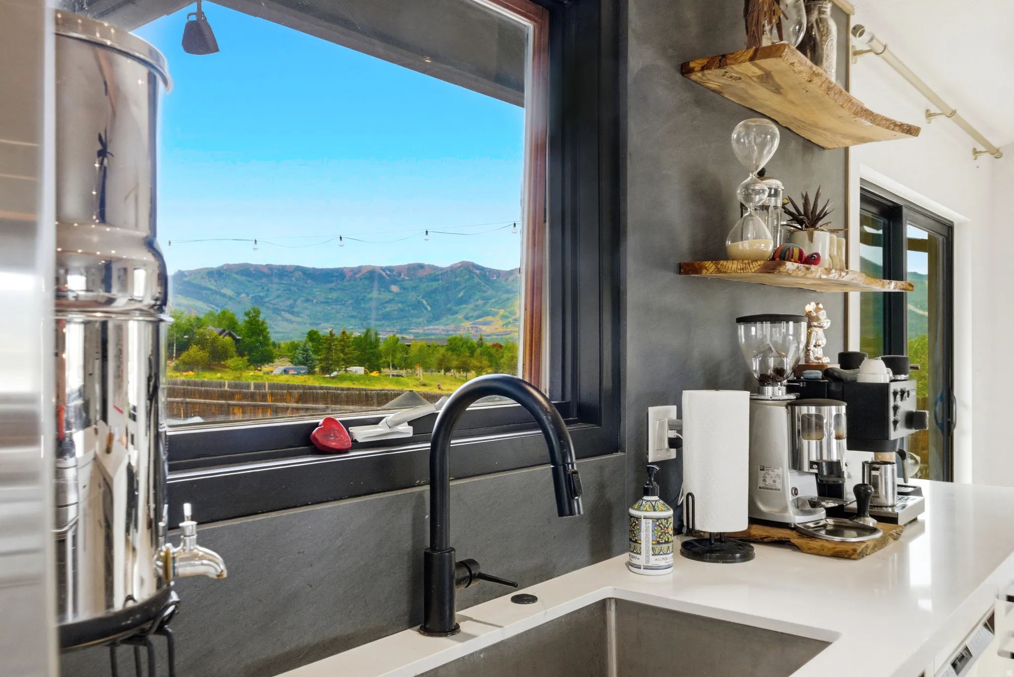 Kitchen sink area featuring a black gooseneck faucet, a light-colored countertop, and a window with a mountain backdrop