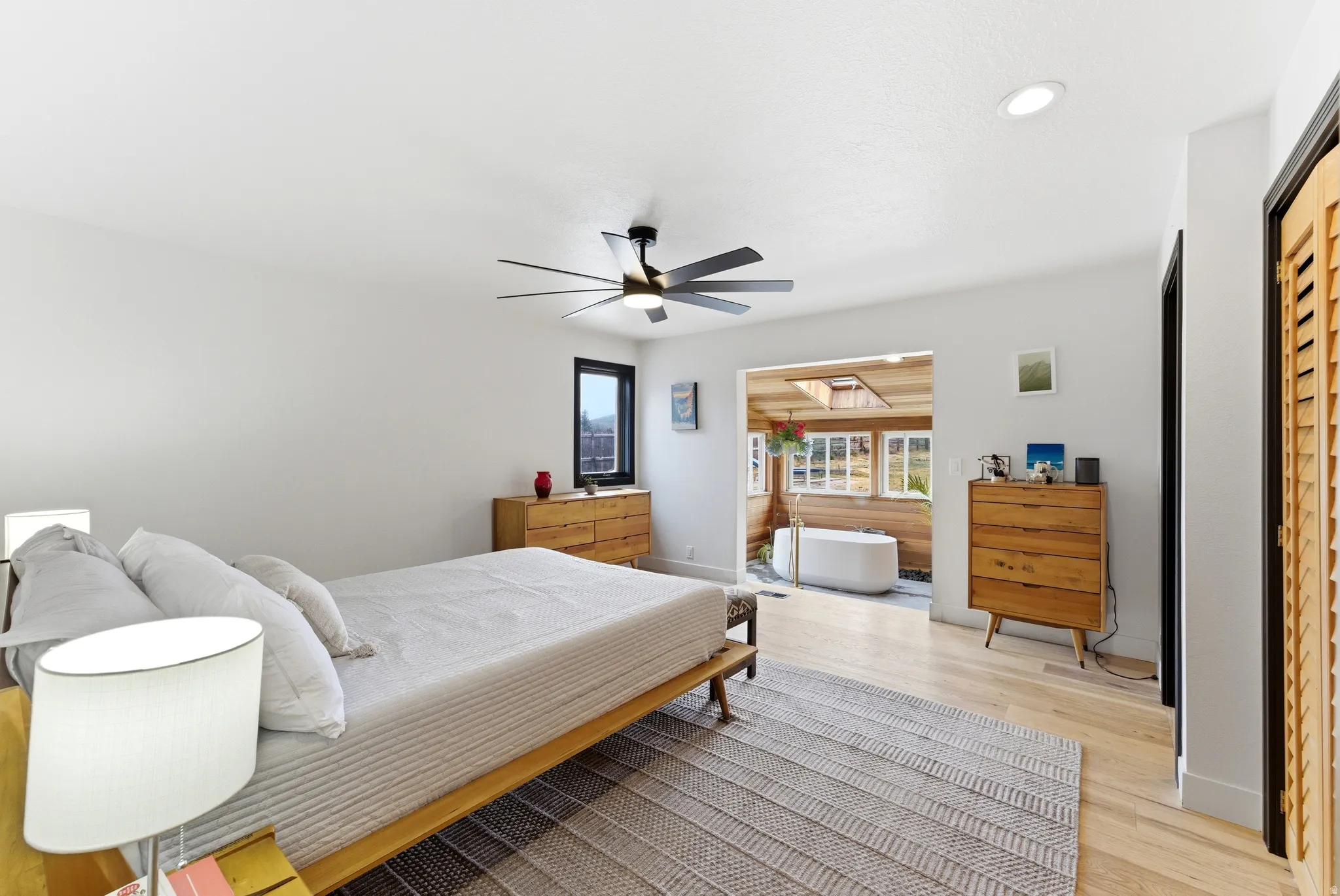 Bedroom featuring light wood-finish flooring, a contemporary ceiling fan, and white walls