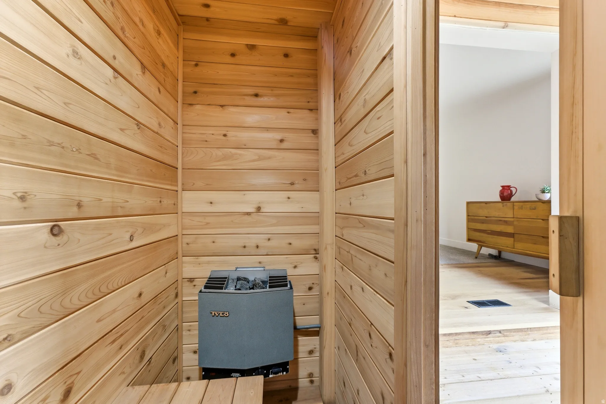 Interior sauna with natural wood paneling and a built-in electric heater
