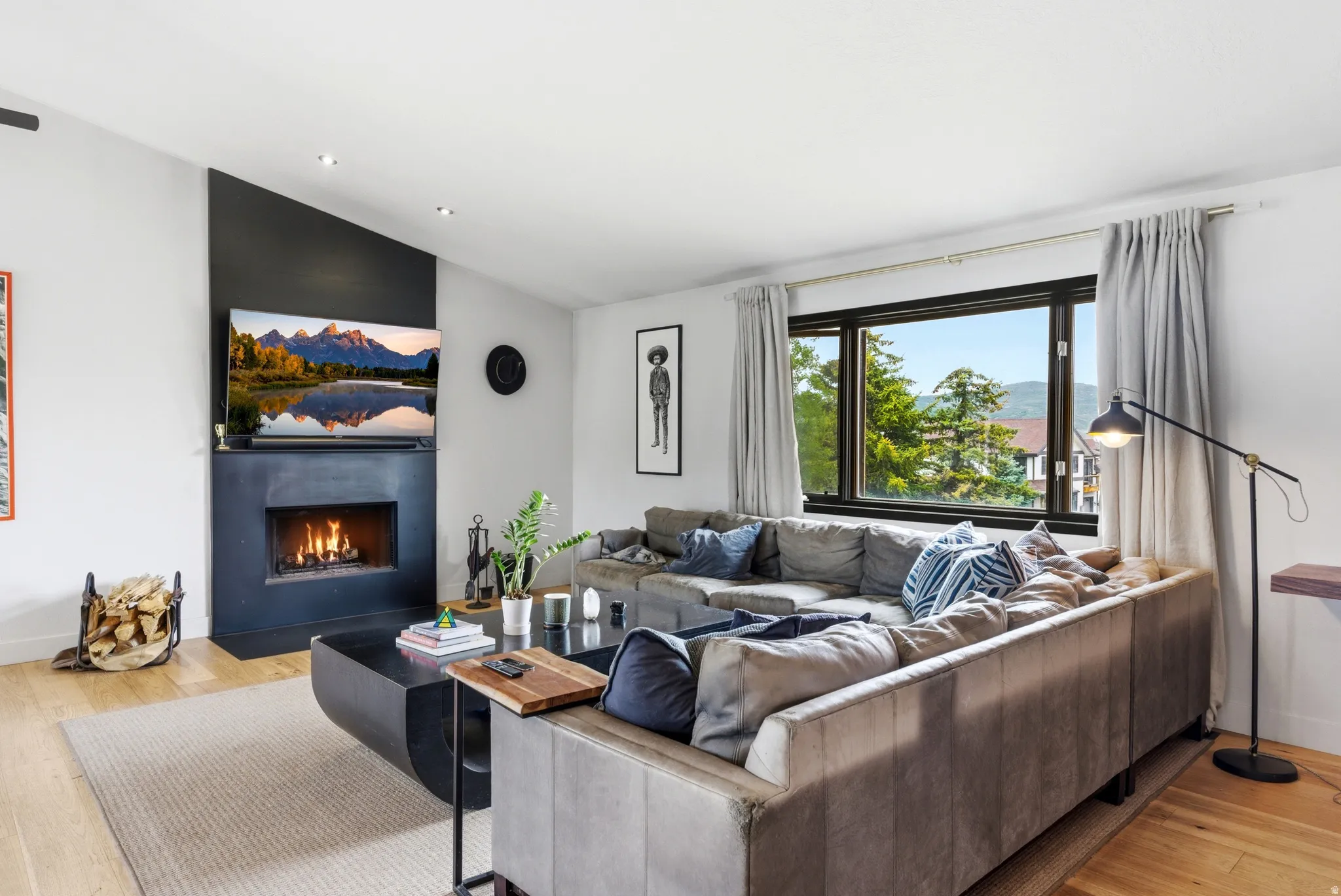 Living area featuring a modern black fireplace with a mantel, recessed lighting, and wood-finish flooring