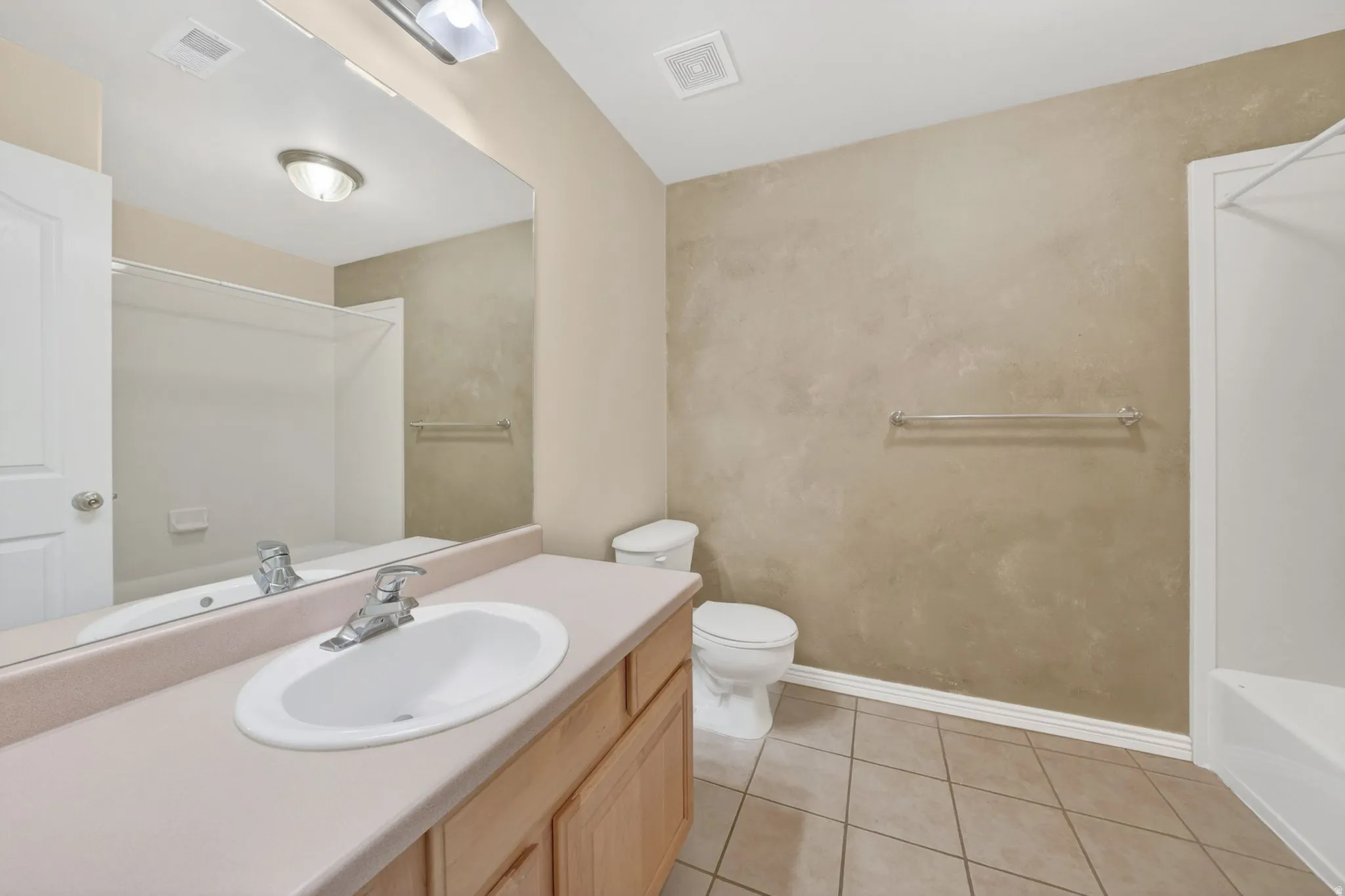 Bathroom featuring a single vanity with an integrated sink, laminate countertop, and wood-finish cabinetry