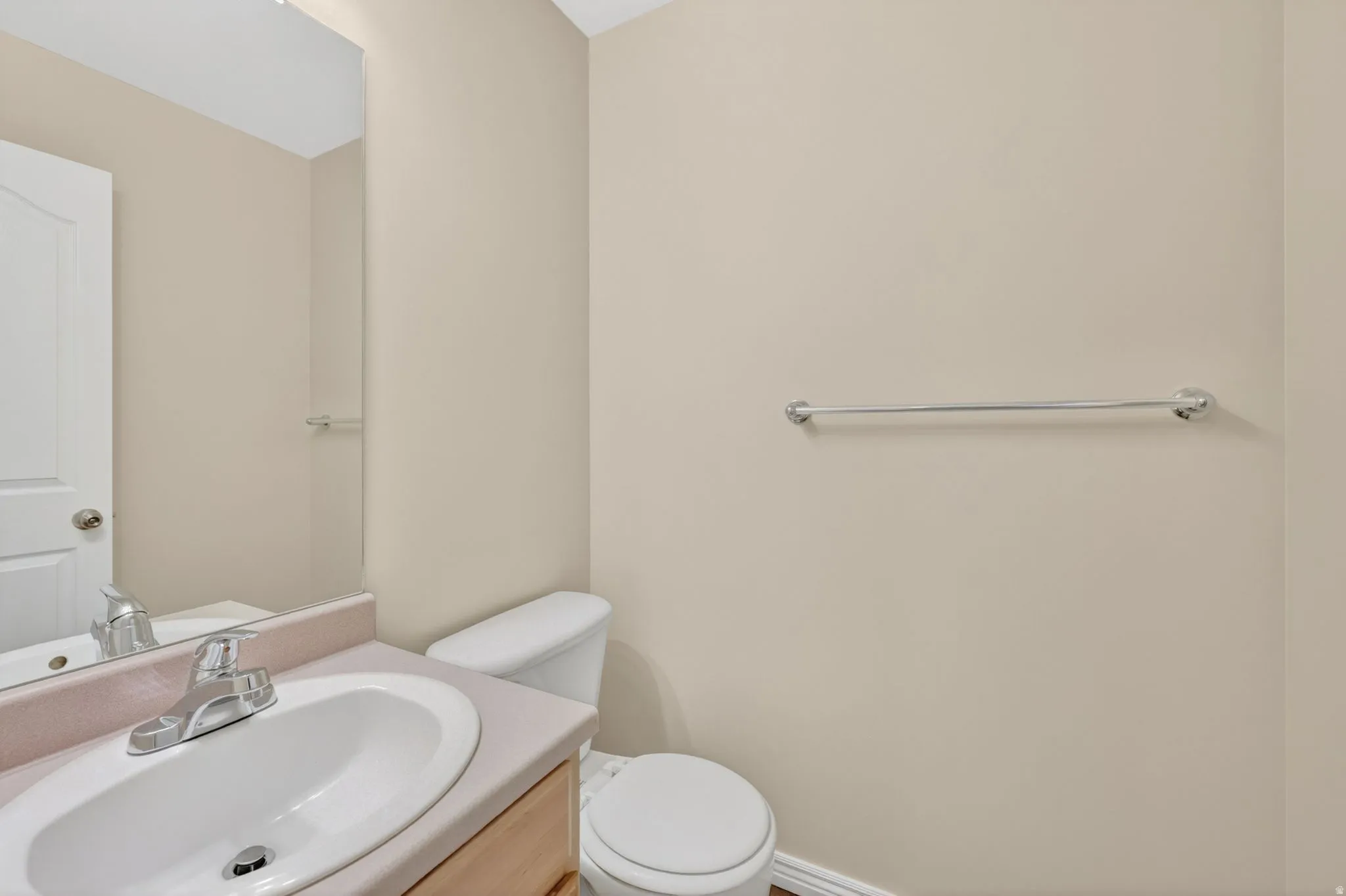 Bathroom featuring a vanity with an integrated sink, polished chrome faucet, full-width mirror, toilet, and wood-finish flooring