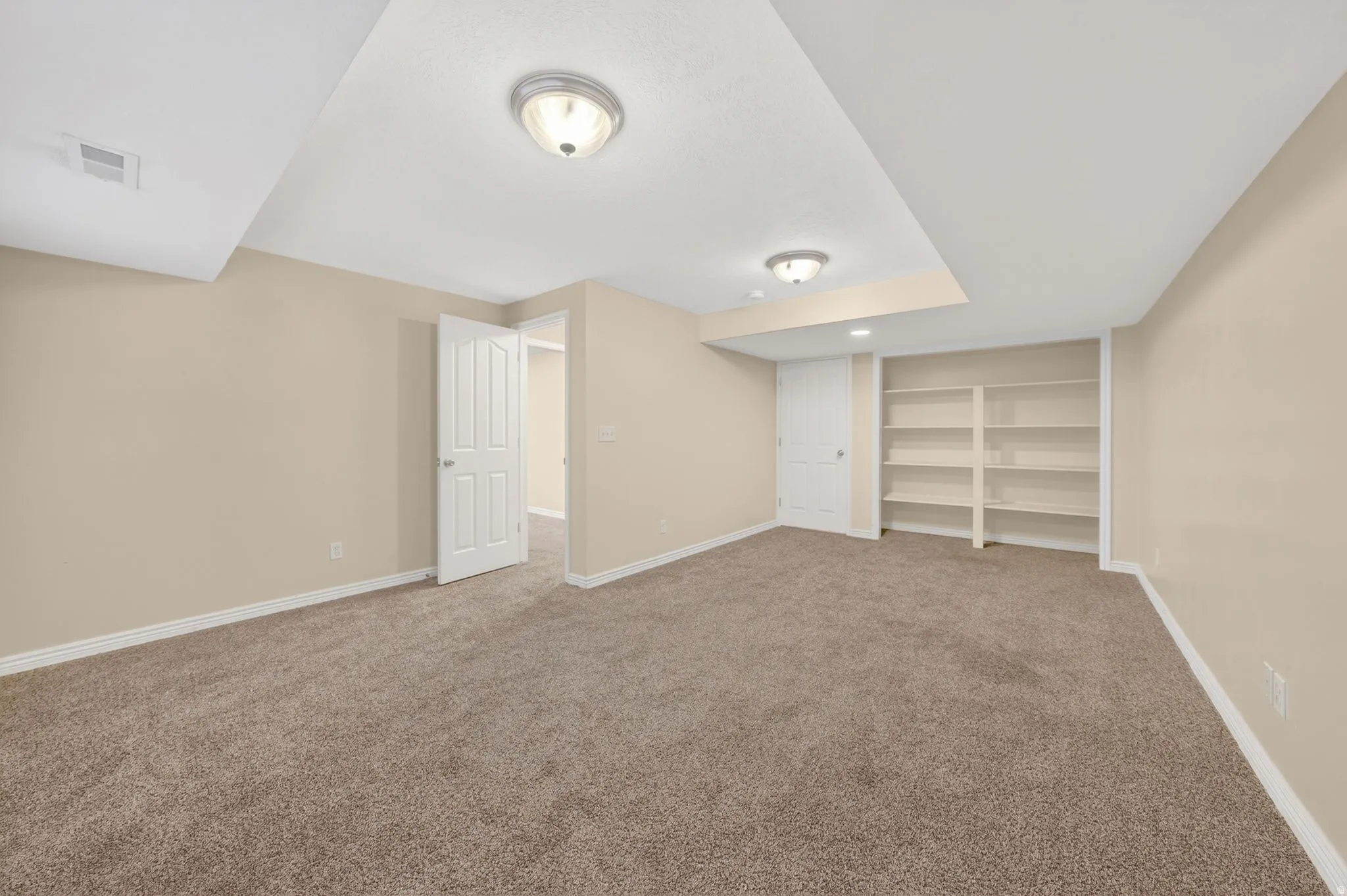 Spacious room featuring neutral carpeting and light-toned walls