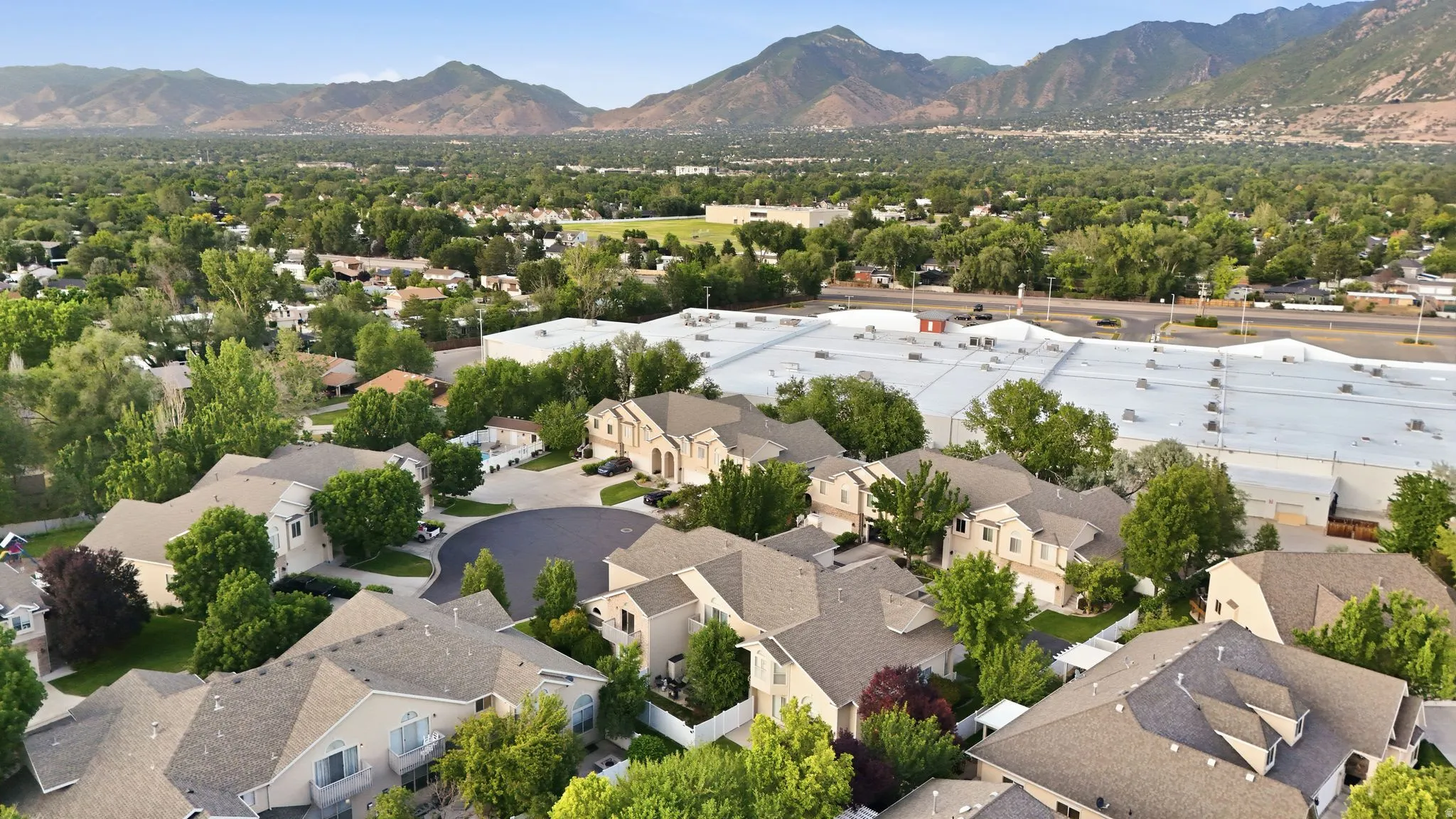 Aerial perspective showcasing a residential community with mature landscaping and mountain scenery