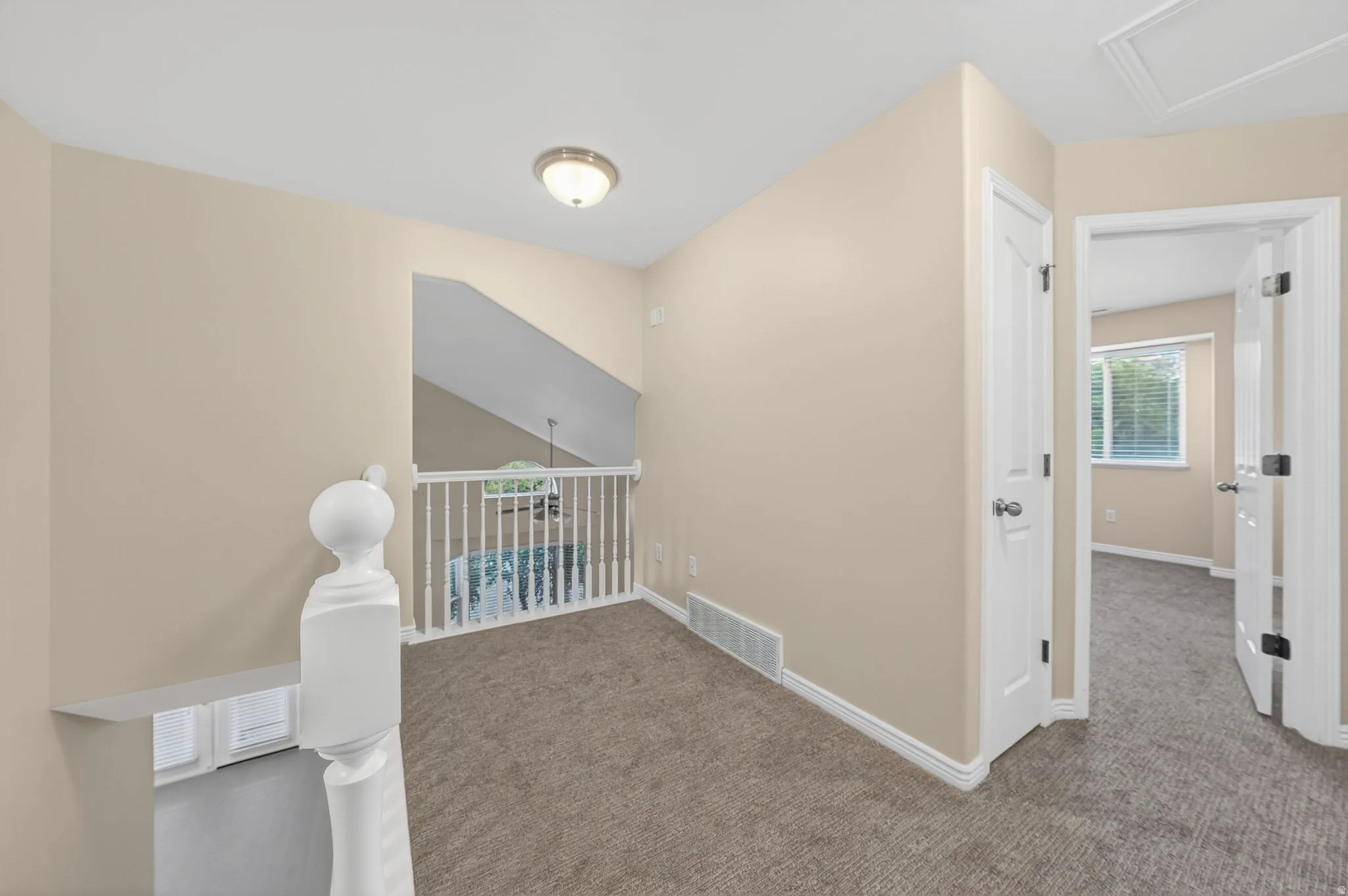 Upper-level landing featuring textured carpeting, neutral wall tones, and white trim