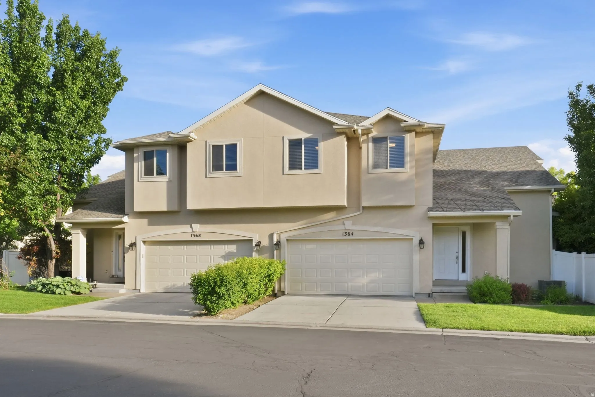 Stucco exterior facade featuring a two-car garage with arched paneling, individual driveways, and covered entryways