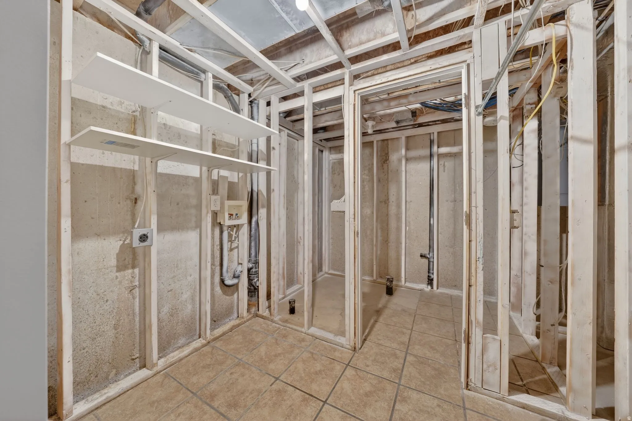 Unfinished room with wood framing, concrete walls, and a tiled floor