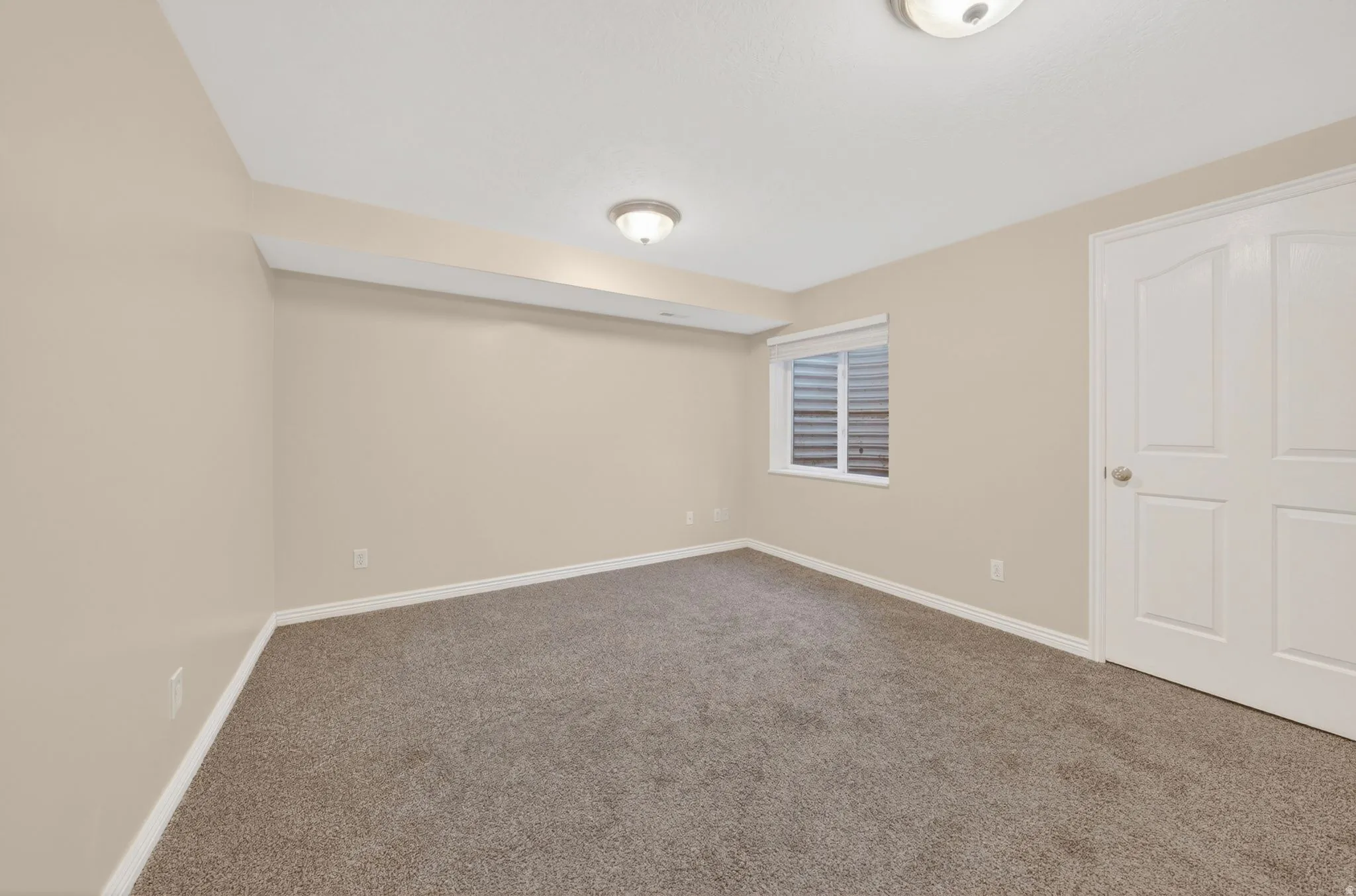 Carpeted room featuring neutral-toned walls, white trim, and a window with blinds