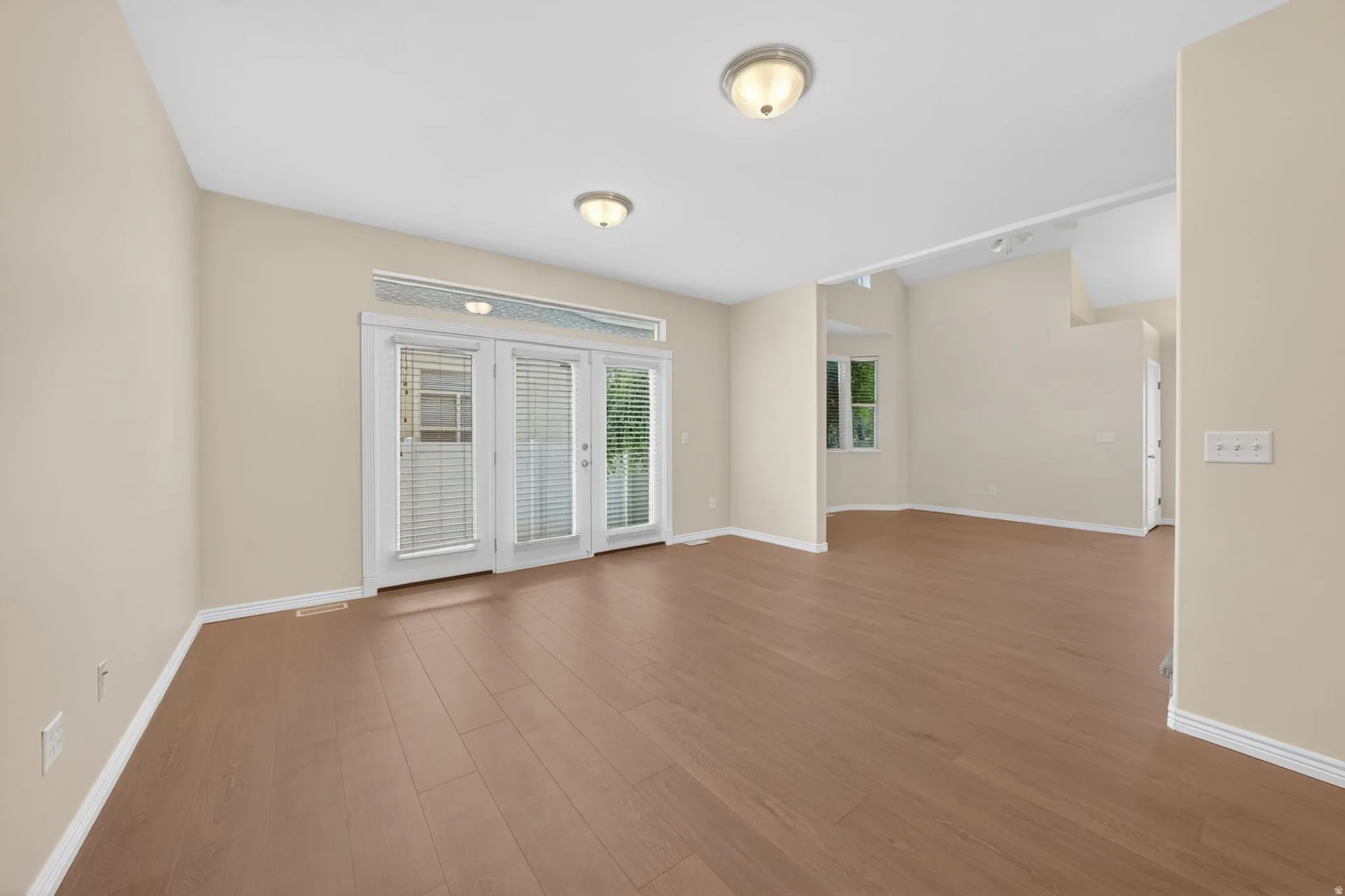 Spacious interior with wood-finish flooring, warm neutral wall tones, and white trim