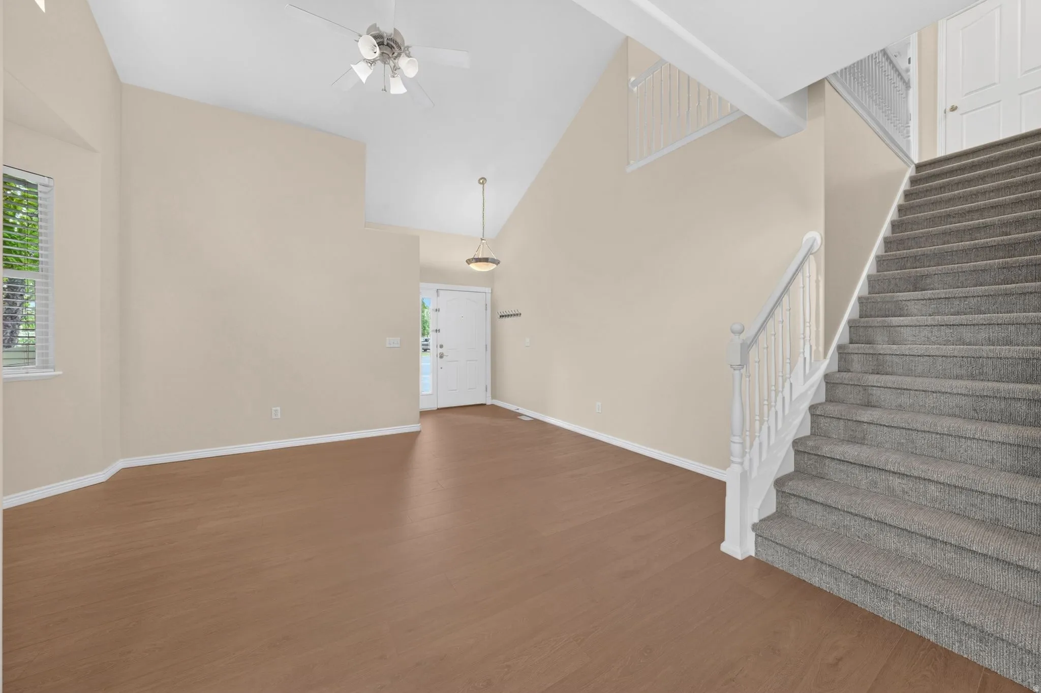 Open-concept room featuring wood-finish flooring, vaulted ceilings, and a ceiling fan