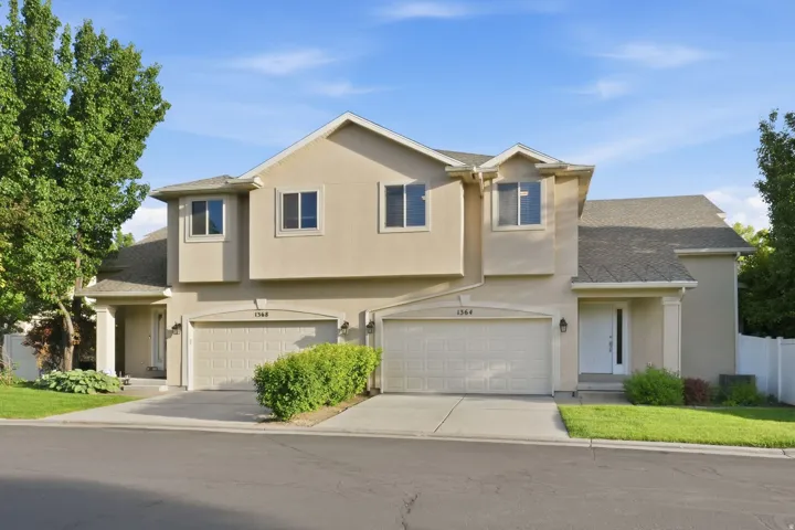 Stucco exterior facade featuring a two-car garage with arched paneling, individual driveways, and covered entryways