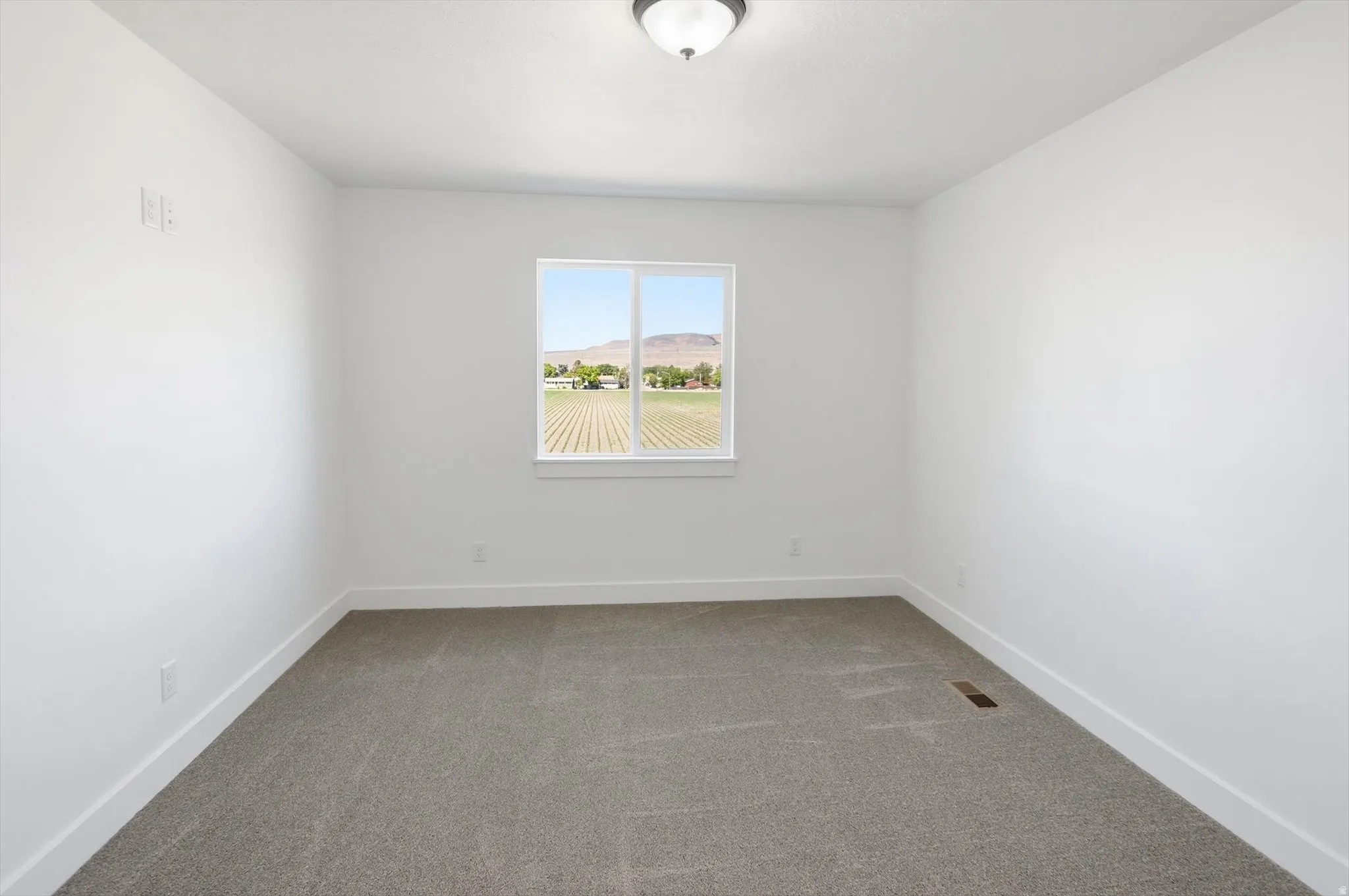 Bright room featuring neutral carpeting, white walls, and a single window