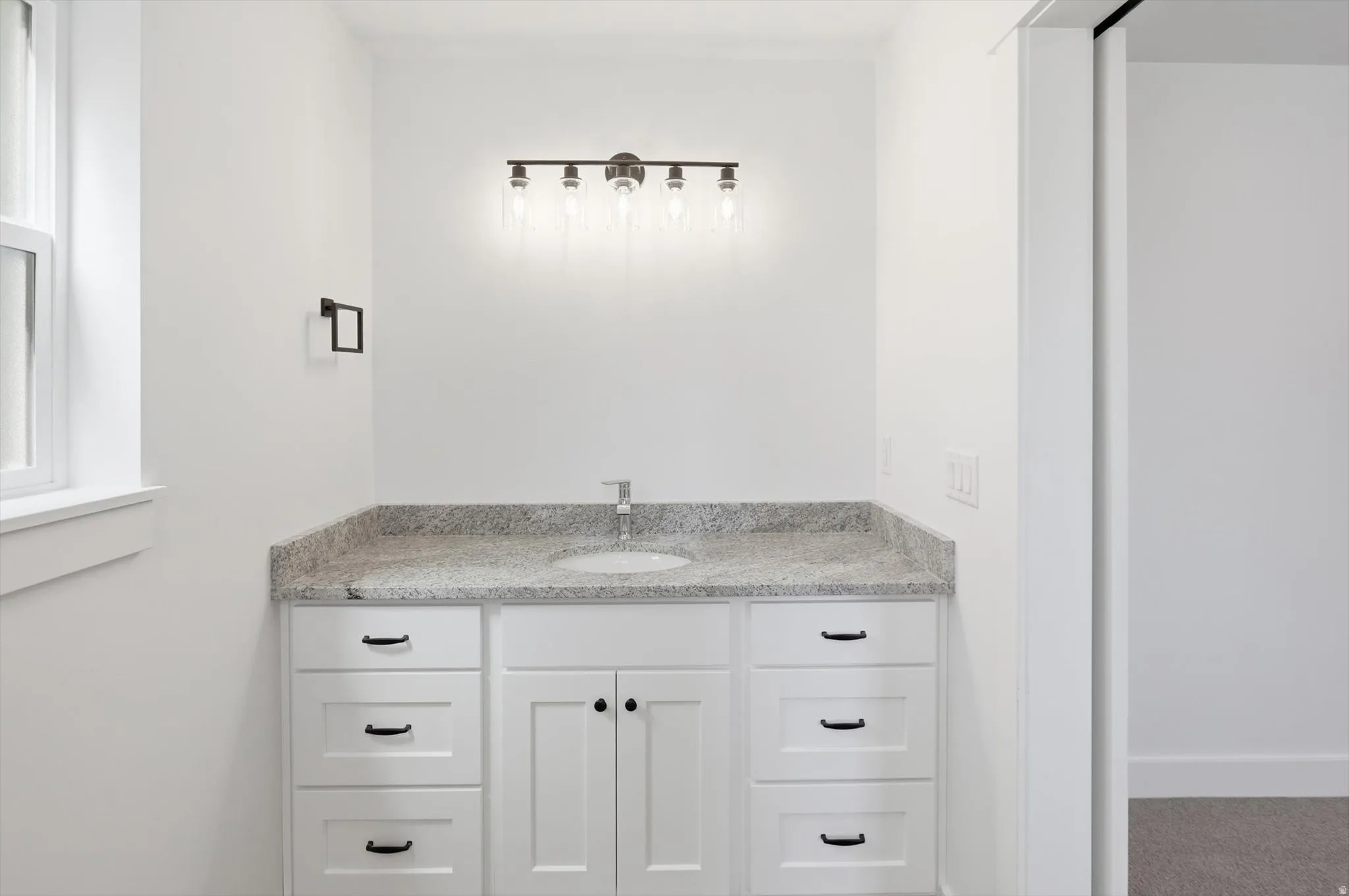 Bathroom vanity with a light-toned countertop, an undermount sink, and a chrome faucet