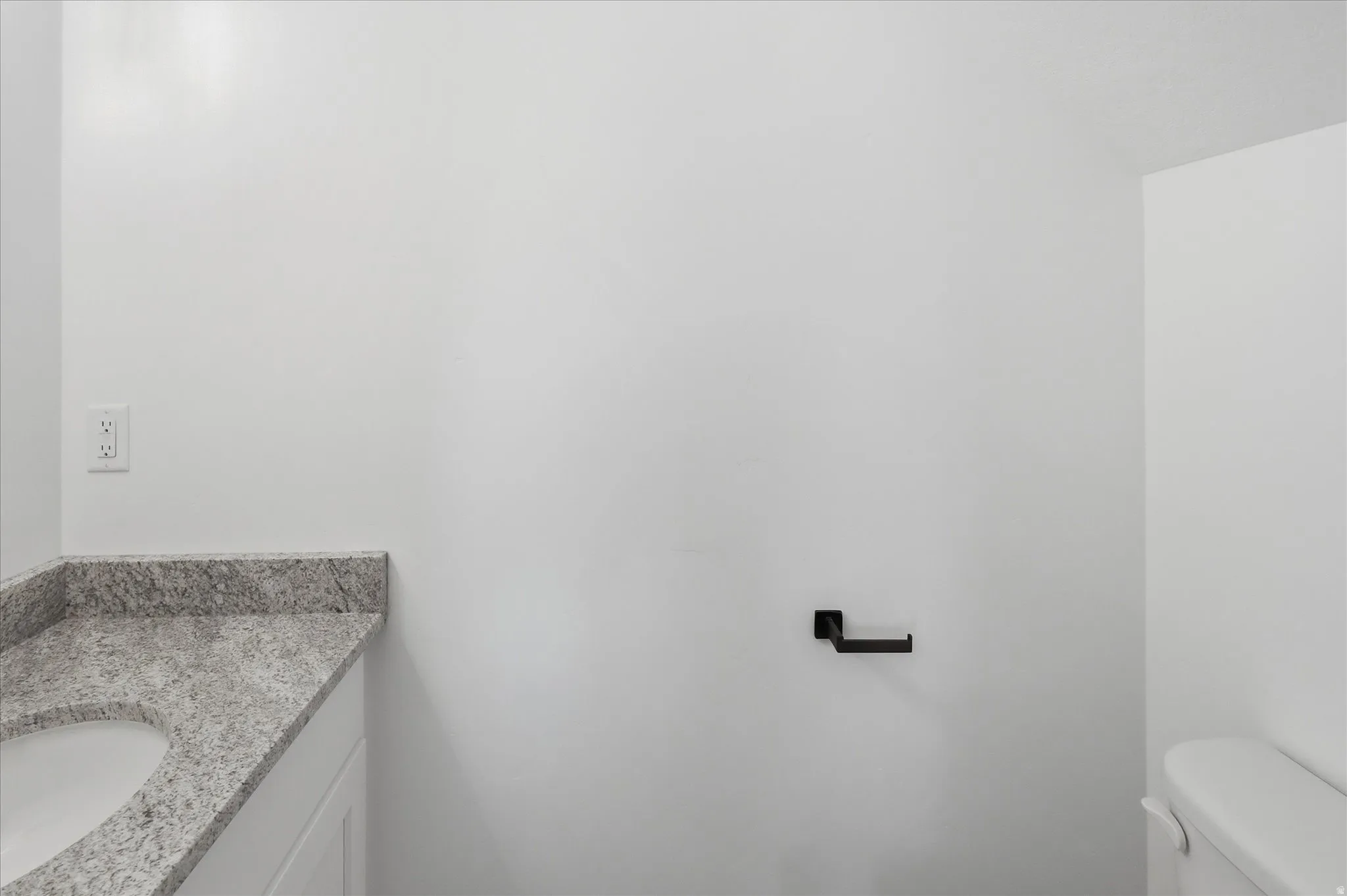 White vanity with a speckled countertop and an integrated oval sink