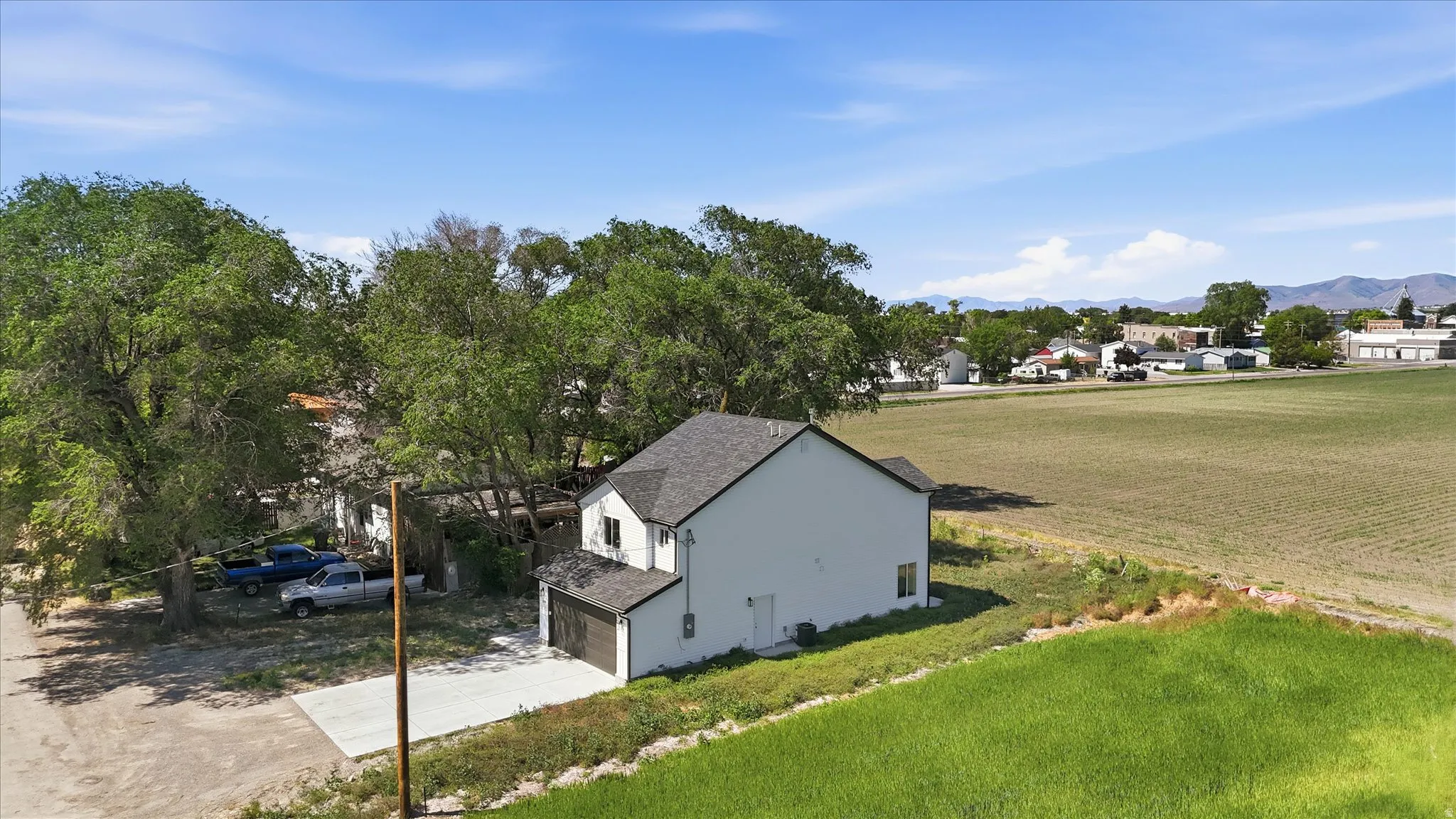 Two-story residence featuring light-toned siding, a dark shingle roof, and an attached two-car garage with a brown door