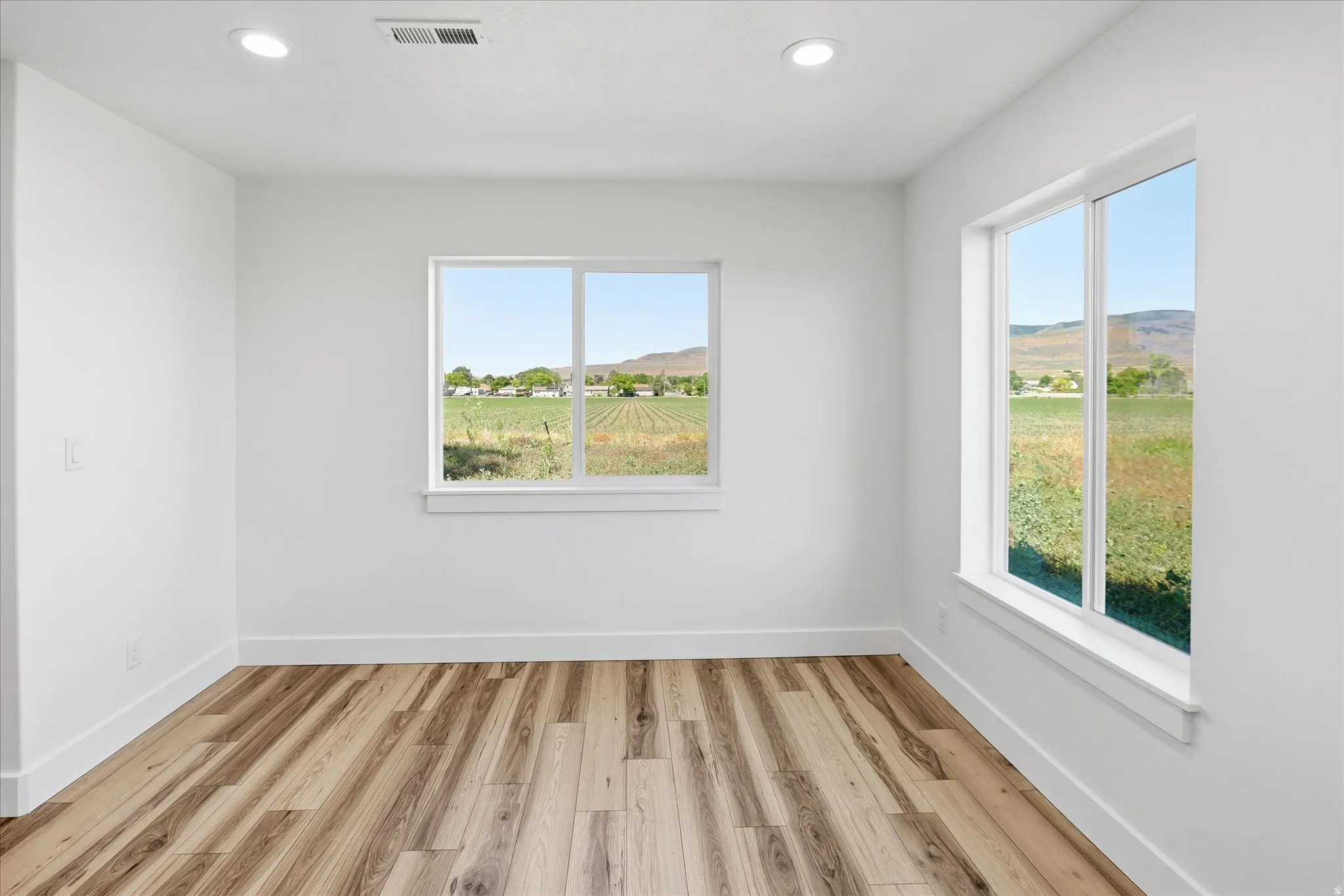 Bright room featuring wood-finish flooring and recessed lighting