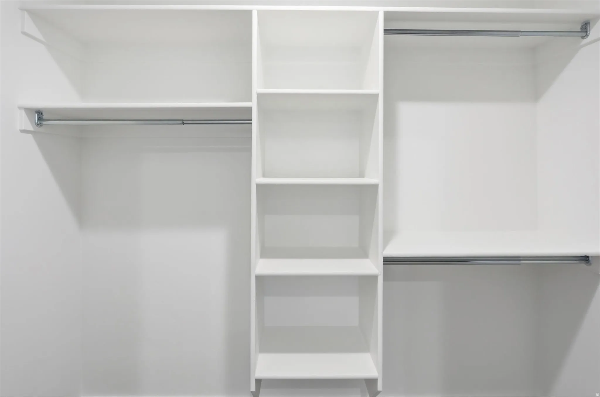 Custom closet organization system featuring white shelving units and chrome hanging rods