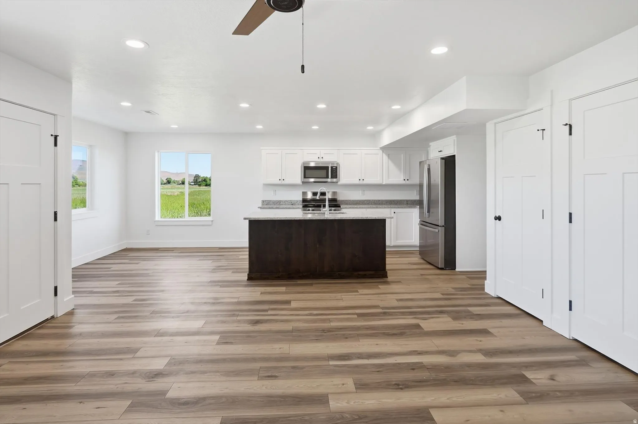 Open-concept kitchen and living area featuring wood-finish flooring, recessed lighting, and a dark-toned kitchen island