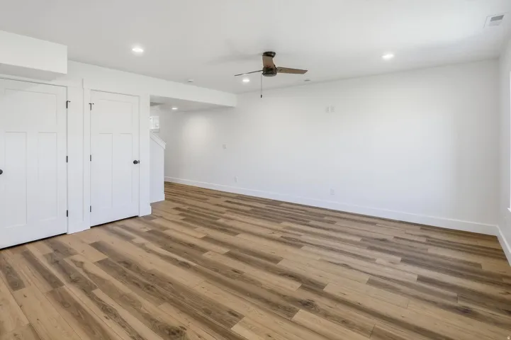Spacious room featuring wood-finish flooring, white walls, and recessed lighting