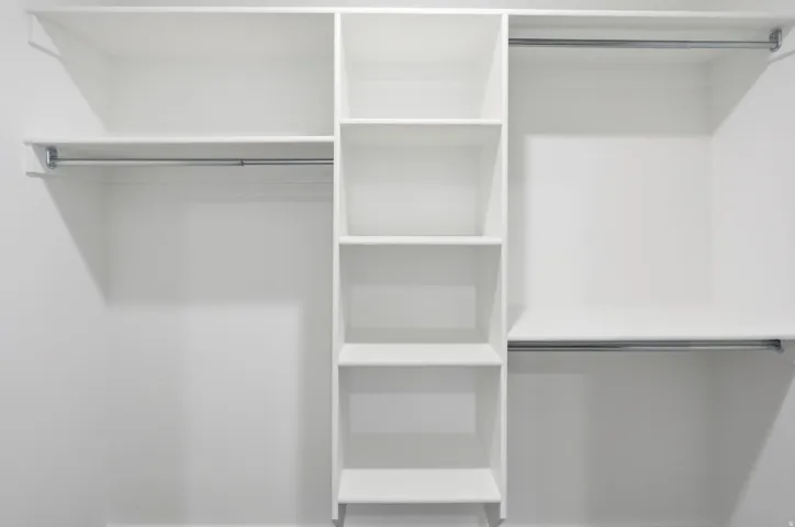 Custom closet organization system featuring white shelving units and chrome hanging rods