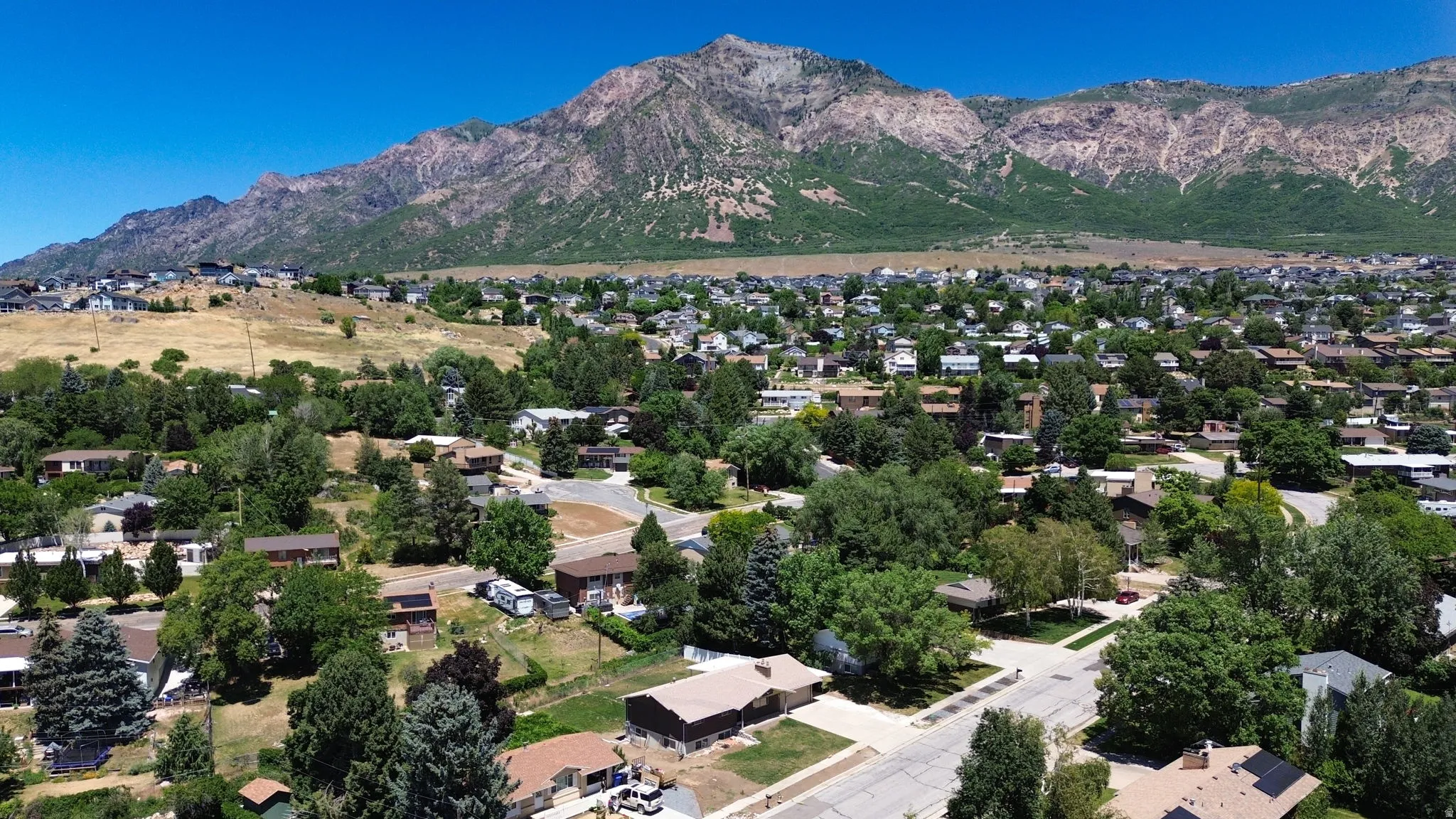 Expansive residential area featuring a mountainous backdrop, mature trees, and a network of streets