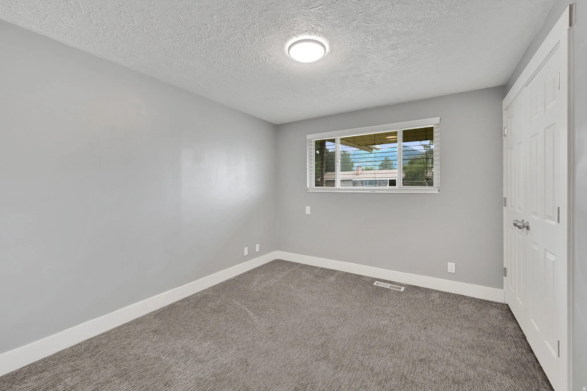 Room featuring light grey walls, white baseboards, and grey carpet flooring