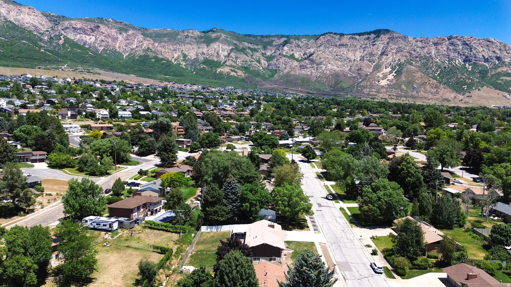 Expansive aerial perspective showcasing a residential neighborhood with established trees and street infrastructure