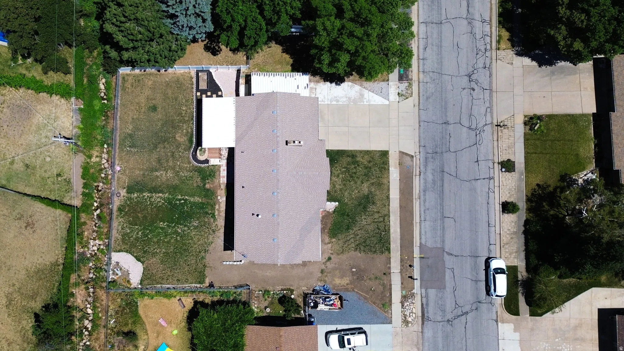 Spacious lot with a residence featuring a brown shingle roof, a rear patio with a white awning, and a partially fenced backyard