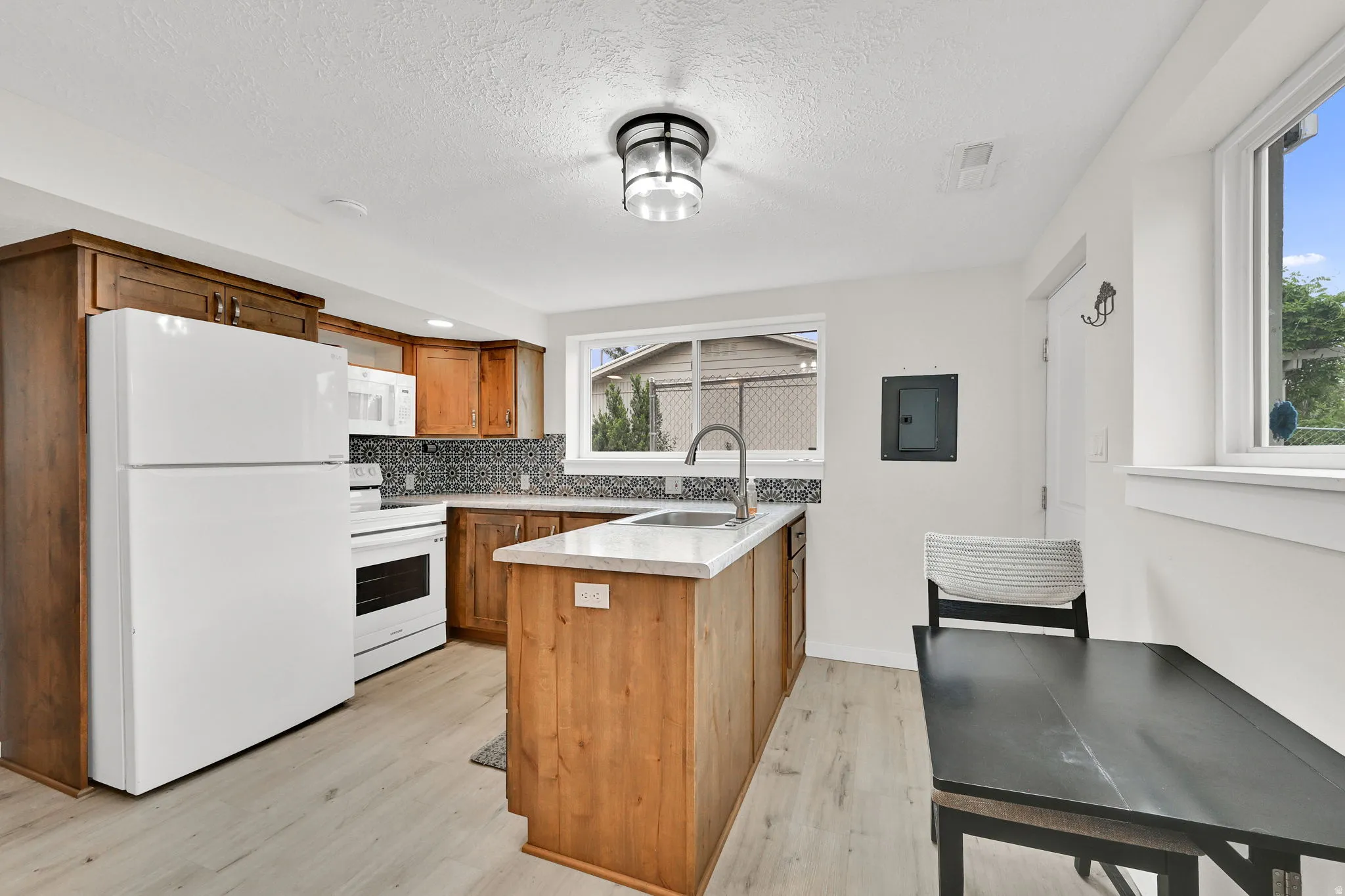 Kitchen featuring wood cabinetry, light-toned countertops, patterned tile backsplash, and light-finish flooring