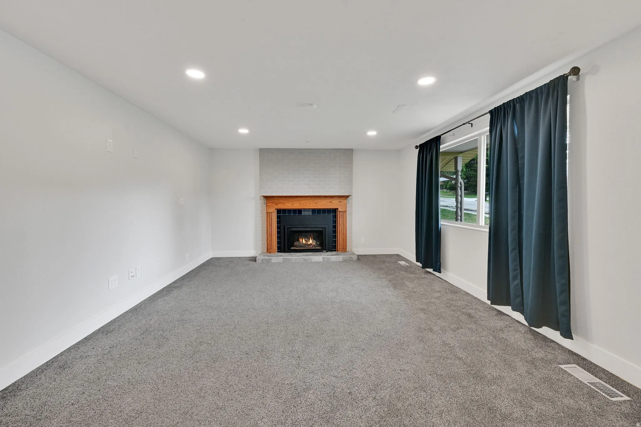 Living area featuring a floor-to-ceiling fireplace with a wood mantel, a black firebox, and a light-colored brick surround