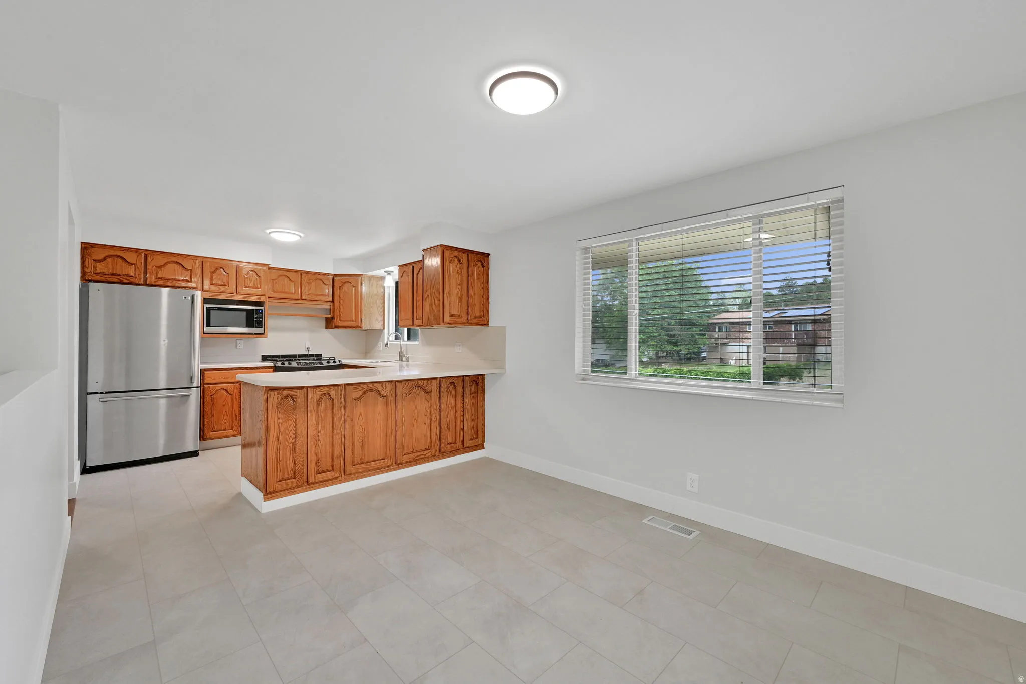 Kitchen and dining area featuring light wood cabinetry, stainless steel appliances, and a gas range