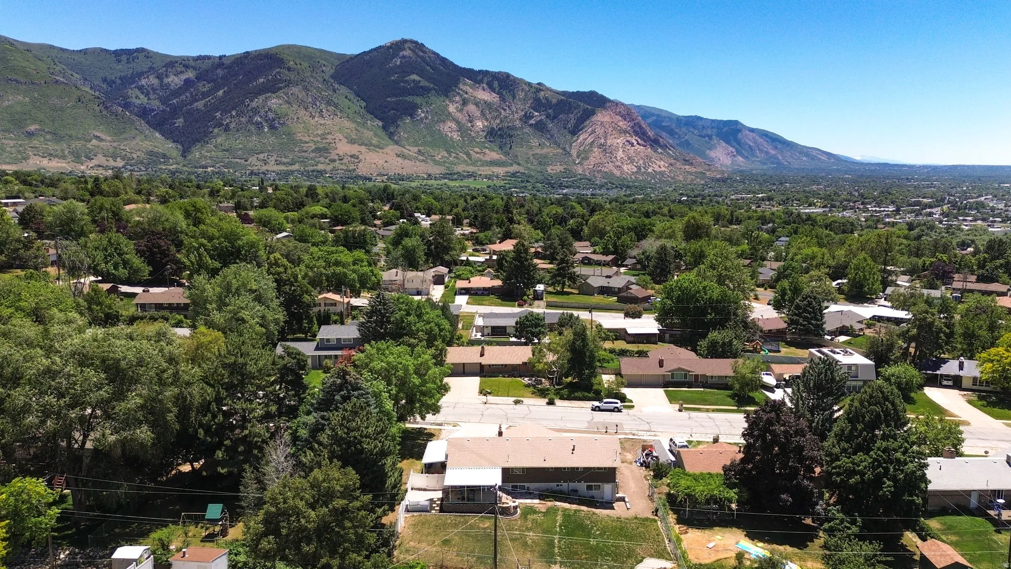 Expansive neighborhood setting with mature trees and mountain backdrop