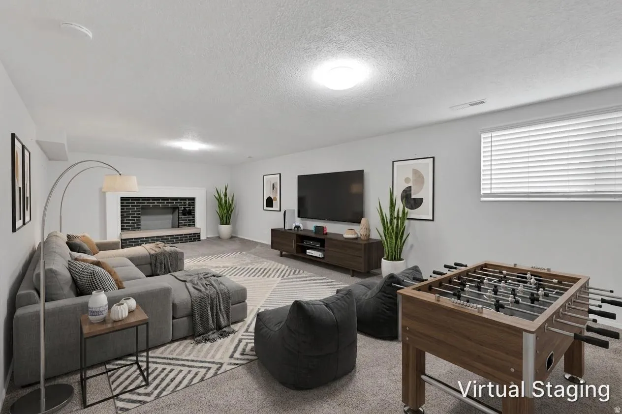 Spacious recreational area featuring a fireplace with a dark brick facade and a wide hearth. Room was virtually staged.