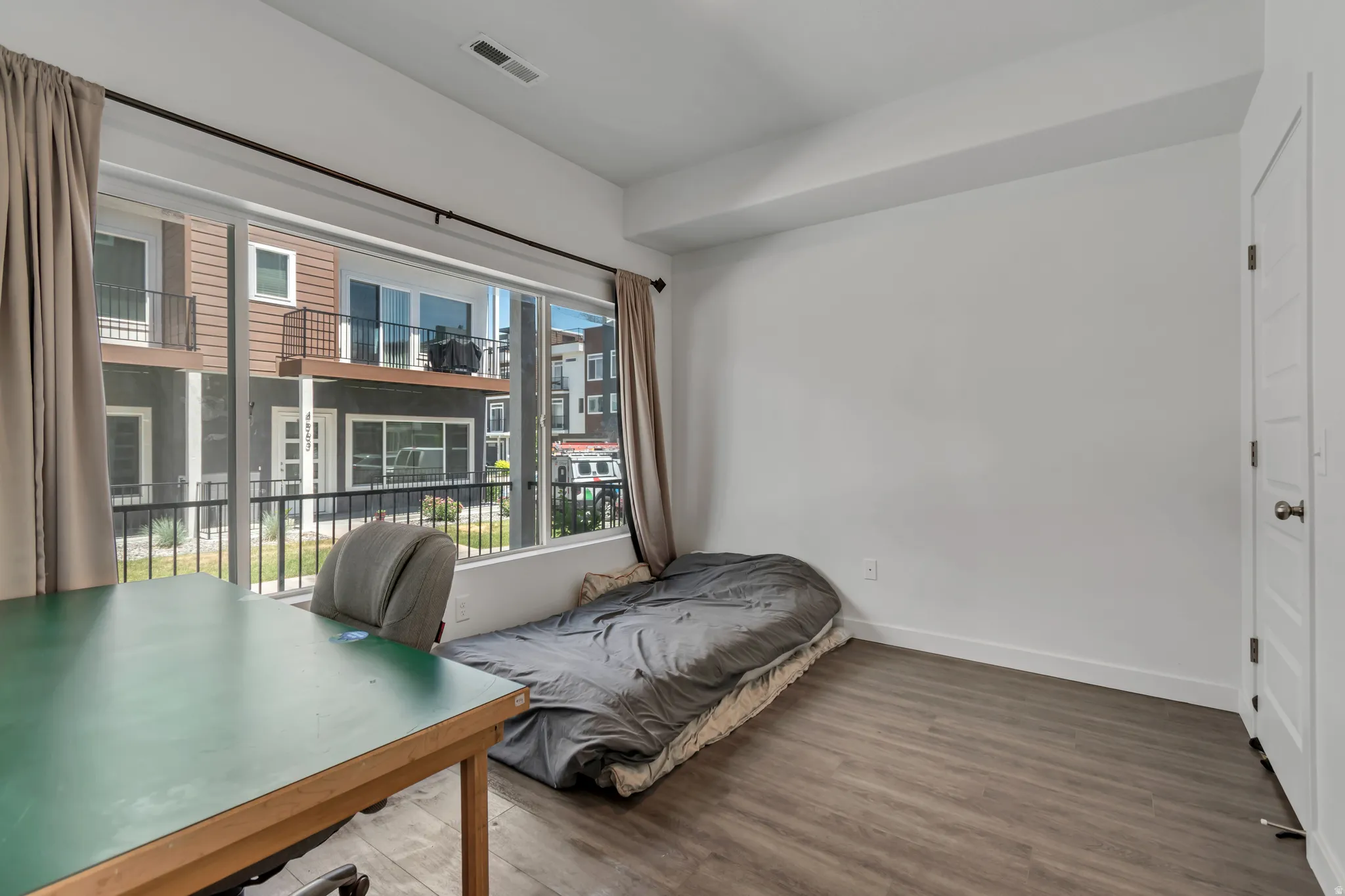 Room featuring wood-finish flooring, a contemporary window wall, recessed ceiling vent, and a white paneled door