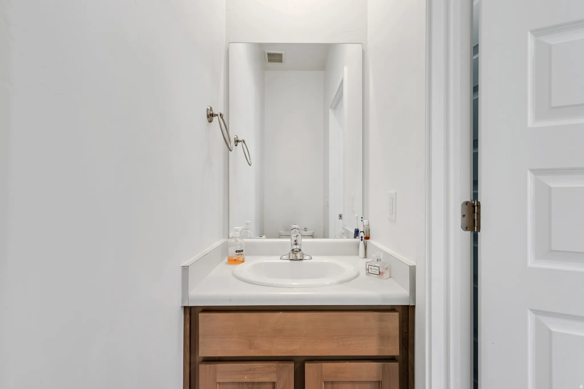 Vanity area featuring a wood-finish cabinet, white countertop with an integrated sink, and a framed mirror