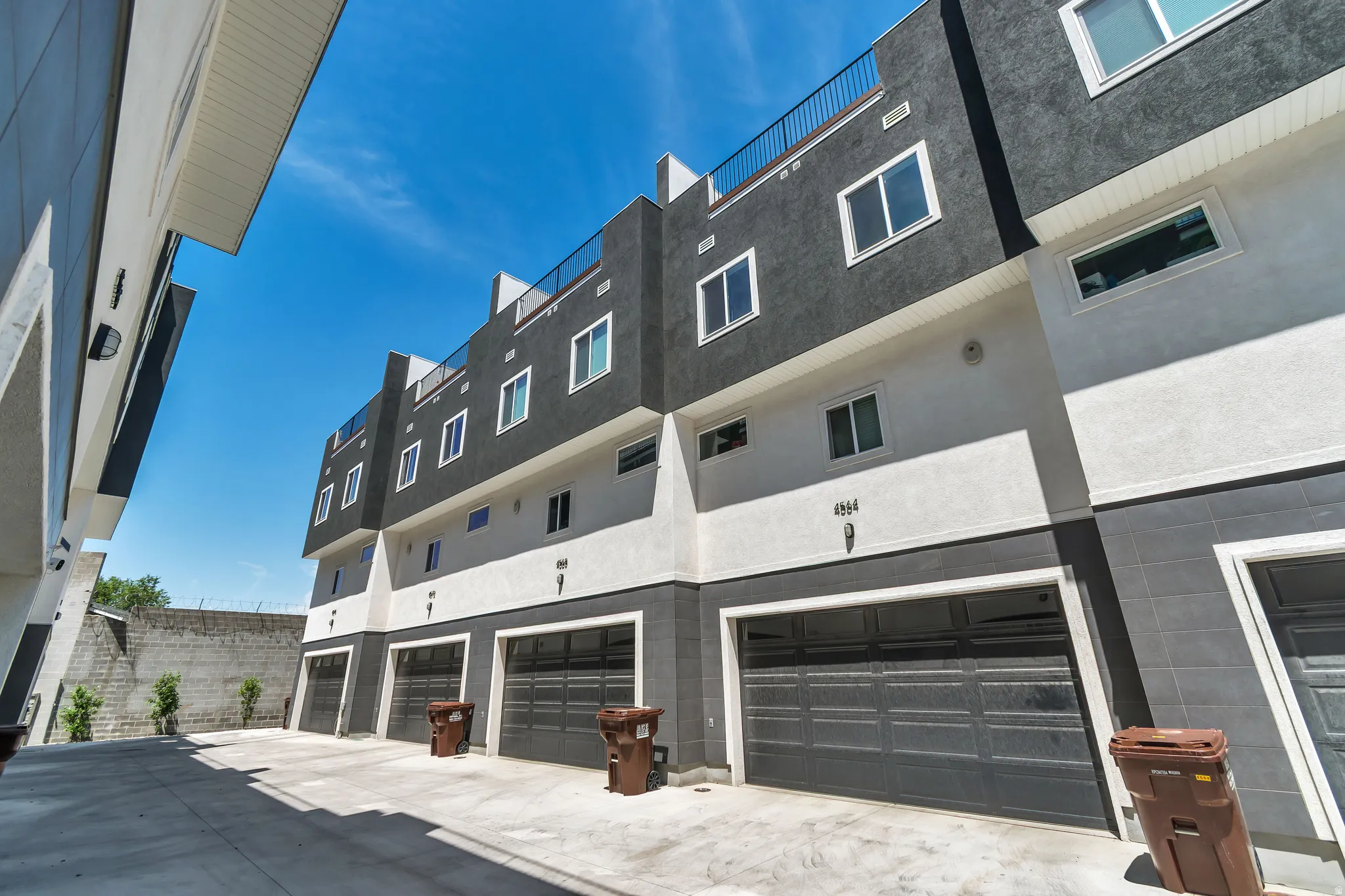 Contemporary multi-story exterior with a two-tone facade, featuring multiple large windows and individual garages with dark paneled doors