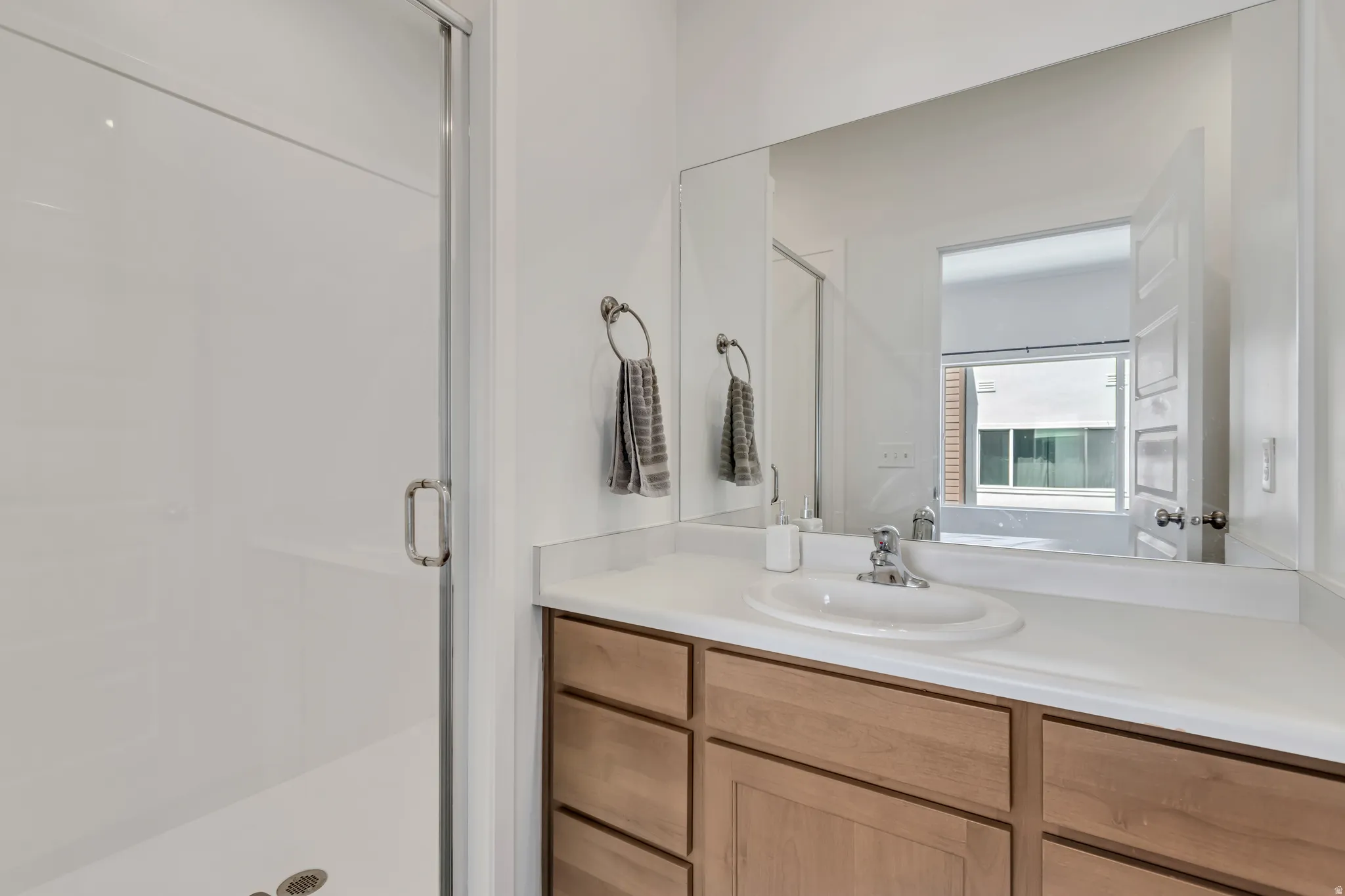 Bathroom featuring a light wood-finish vanity with an integrated sink and a neutral-toned countertop