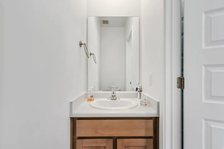 Vanity area featuring a wood-finish cabinet, white countertop with an integrated sink, and a framed mirror