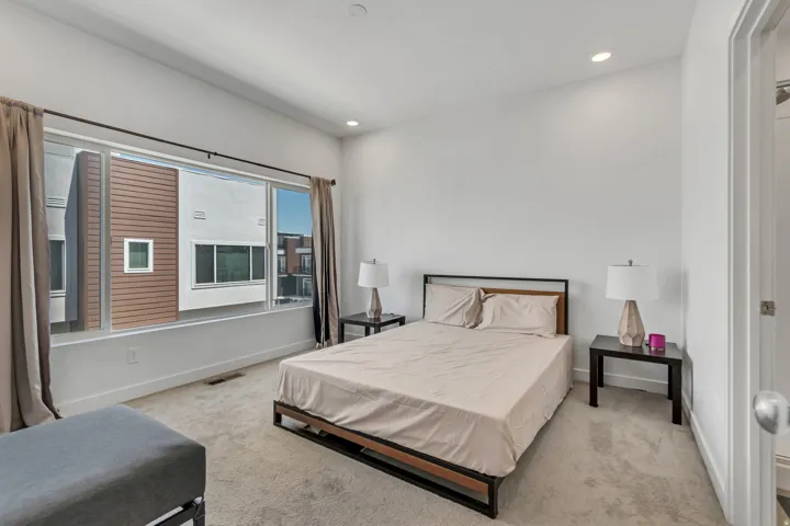 Spacious interior featuring a large window with privacy blinds, recessed lighting, and light-toned carpet flooring